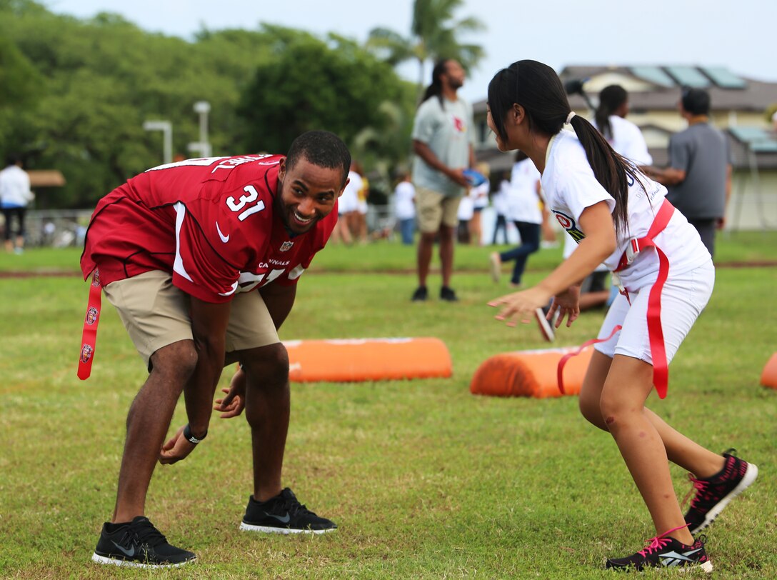 Justin Bethel, cornerback for the Arizona Cardinals, tries to grab a flag from a Mokapu student during the NFL Play 60 event, Jan. 22, 2014. (U.S. Marine Corps photo by Lance Cpl. Suzanna Knotts)