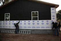 Marines with Alpha Company, 8th Engineer Support Battalion, 2nd Marine Logistics Group attach a layer of insulation to a Cape Carteret, N.C. home as part of a volunteer project with Habitat for Humanity International, Jan. 23, 2014. Marines with Alpha Co. have installed windows, roof shingles and tar paper to the house, and plan on continuing to add to it whenever they are needed. (U.S. Marine Corps photo by Lance Cpl. Shawn Valosin)