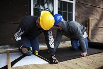 Marines with Alpha Company, 8th Engineer Support Battalion, 2nd Marine Logistics Group measure and cut tar paper before attaching it to a house while helping out Habitat for Humanity International at a Cape Carteret, N.C. home, Jan. 23, 2014.Ten combat engineers with Alpha Co. volunteered to help with the house, and said they like being able to give back to the community. (U.S. Marine Corps photo by Lance Cpl. Shawn Valosin)