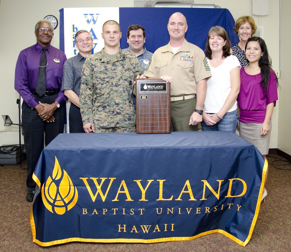 Sgt. Michael Joseph (third from left), the avionics noncommissioned officer in charge at Marine Light Attack Helicopter Squadron 367, and Master Sgt. Marion Eggers (fifth from left), the operations chief for Explosive Ordnance Disposal at Marine Corps Base Hawaii, pose for a photo with family, Marine Corps Community Services and Wayland Baptist University staff after receiving WBU’s new Loretta Cornett-Huff Memorial Scholarship in classroom B at the Education Center, Jan. 21, 2014. (U.S. Marine Corps photo by Kristen Wong)