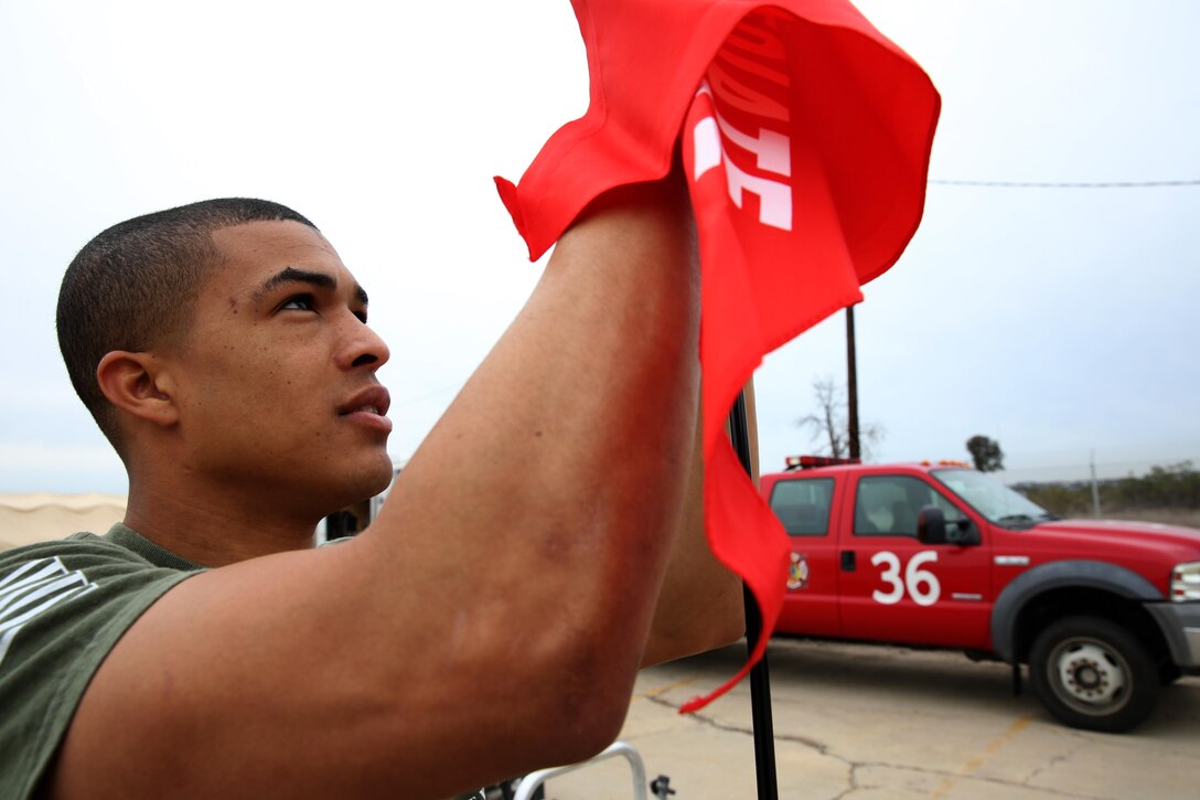 Pfc. Aaron Allen, water turret operator with Aircraft Rescue and Firefighting and also hazardous materials technician with the exercise, hangs a marking flag during a practical application portion of a hazardous materials course at the Explosive Ordnance Disposal complex aboard Marine Corps Air Station Miramar, Calif., Jan. 24. The flag will notify medical teams of which groups of simulated casualties need the most care, and in what order, or they may die.