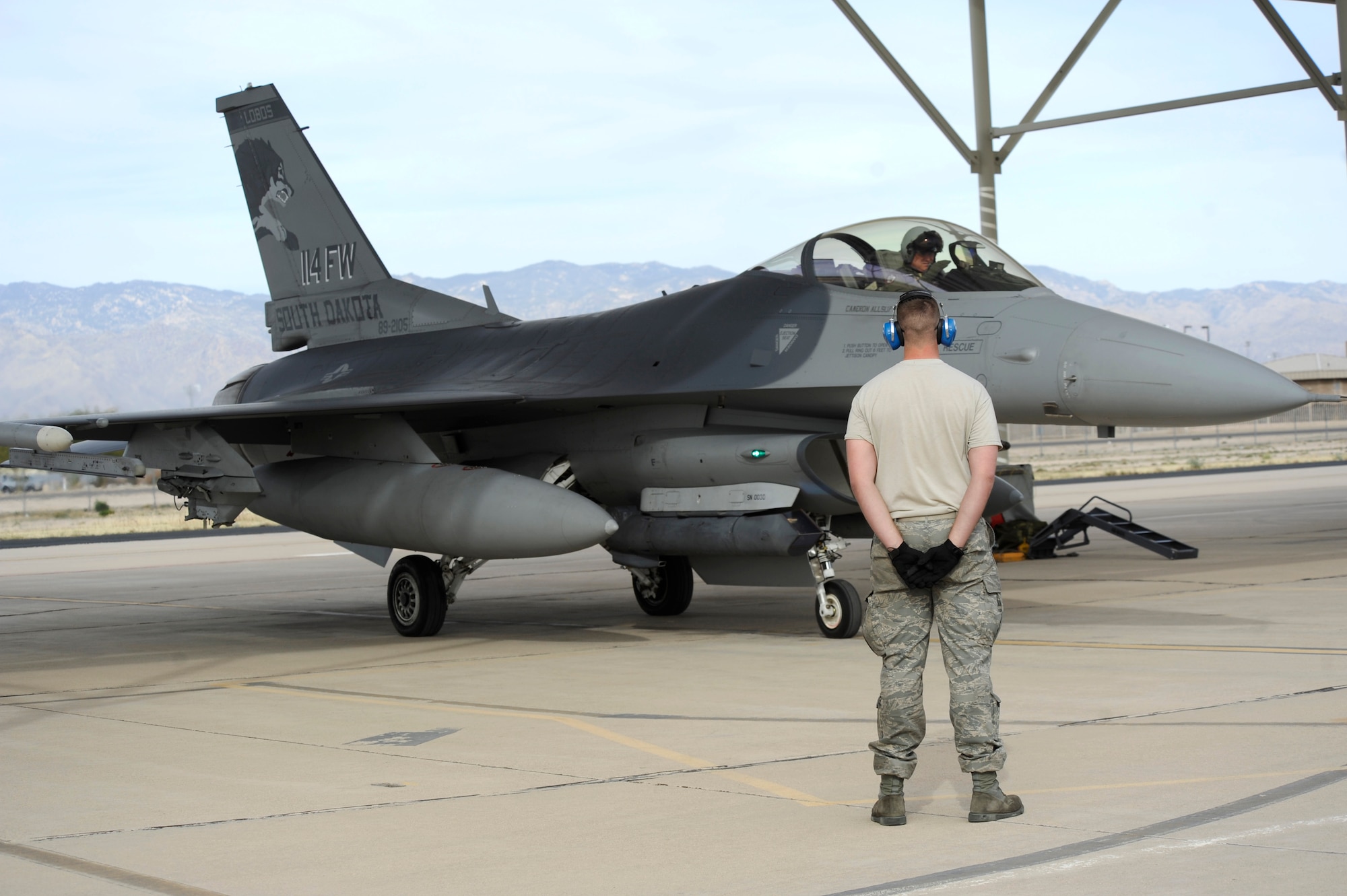 U. S Air Force Staff Sgt. Zack Frank, 114th Aircraft Maintenance Squadron crew chief, stands by while Col. Russ Walz, 114 Fighter Wing commander, pre-flight checks before being taxied onto the runway at Davis-Monthan Air Force Base, Ariz., Jan. 23, 2013. The commander and personnel for the South Dakota Air National Guard travelled to D-M to conduct mandatory training that can be difficult to accomplish during the harsh winter in South Dakota. (U.S. Air Force photo by Airman 1st Class Betty R. Chevalier/released)