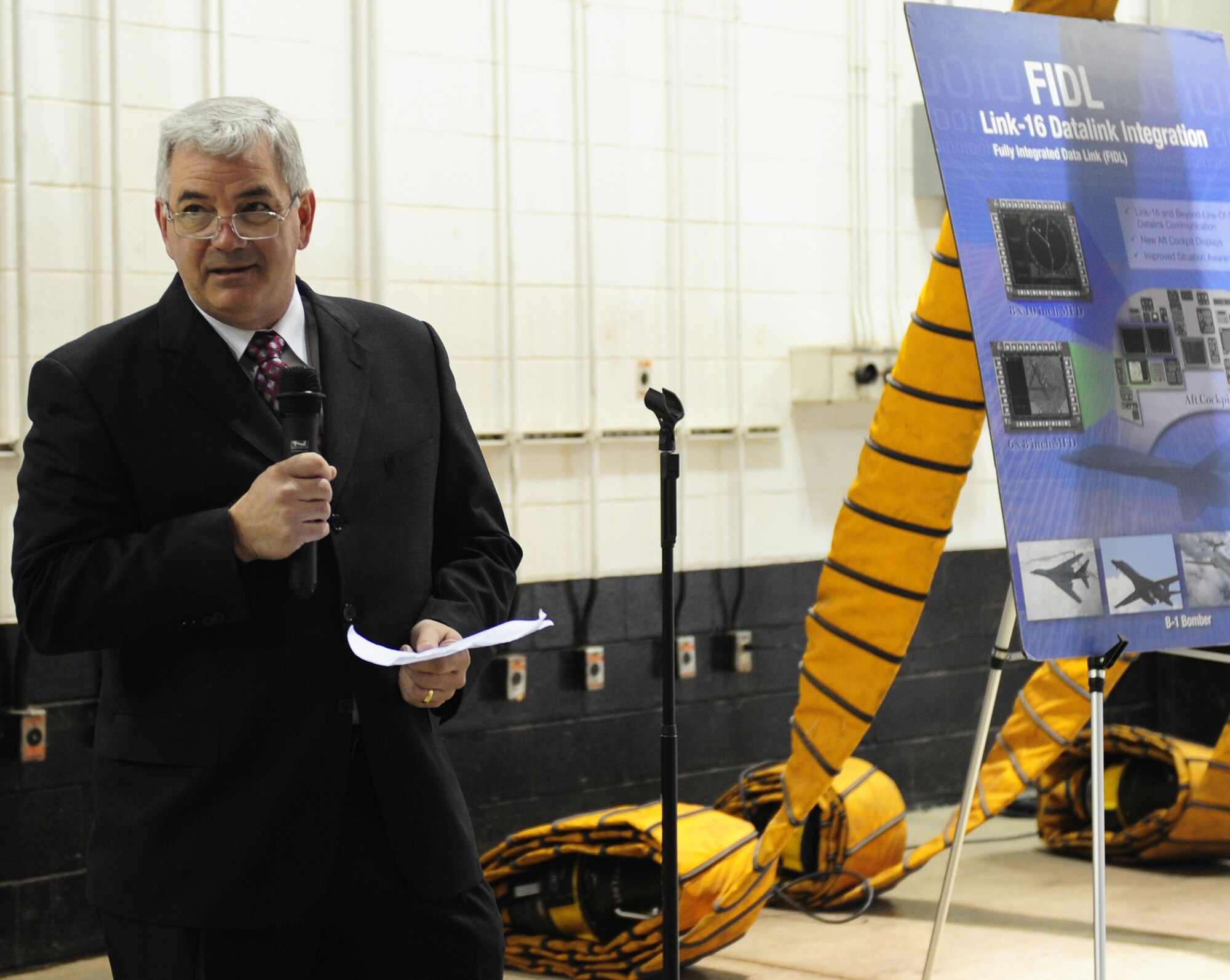 Paul Curlett, Integrated Battle Station Production senior manager, speaks during the B-1 IBS ceremony Jan. 24, 2014 at Dyess Air Force Base, Texas. Dyess received the first operational B-1B Lancer with the Integrated Battle Station upgrade Jan. 21, 2014. The upgrades will affect both aircrew and maintainers by potentially eliminating at least 30 minutes per ground test, reducing the risk of human error from having to key in each test function. (U.S. Air Force photo by Senior Airman Kia Atkins/Released)