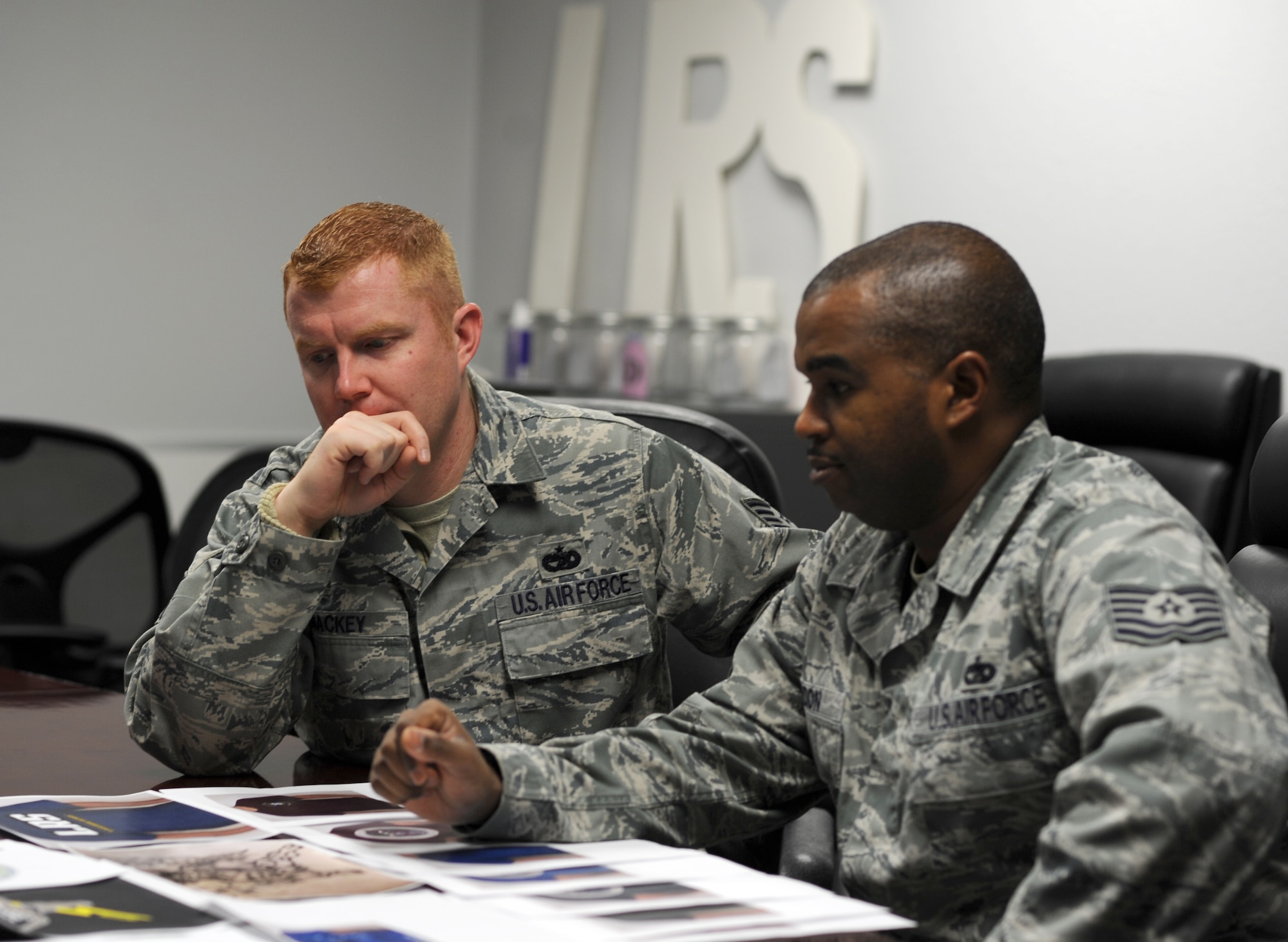U.S. Air Force Tech Sgt. Patrick Mackey (left), 366th Logistics Readiness Squadron NCO in charge of training and validation operations and Tech Sgt. Greg Gordon, 366 LRS NCO in charge of vehicle operations and control center look at squadron t-shirt designs.  “In support of the new [Air Force Instruction] we are coming up with a new squadron t-shirt for Fridays. We are having Airmen throughout our squadron make designs where we will then vote which will be our new T-shirt to boost squadron morale,” said Mackey. The revision to Air Force Instruction 36-2903 paragraph 6.5.2.1. states, “Squadron commanders may authorize Airmen to wear a standardized color undershirt on Friday (only one color per squadron; individual purchase only, not unit-funded).”  (U.S. Air Force photo by Airman 1st Class Brittany A. Chase/Released)