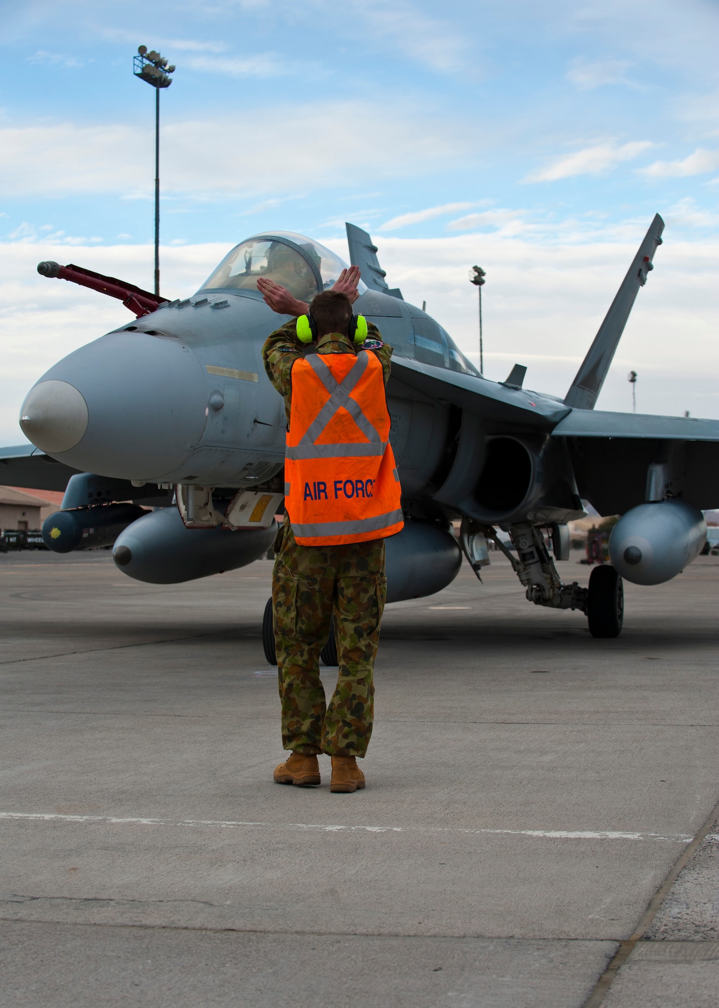 Royal Australian Air Force Lead Aircraftsman Cal Dempsey, 77th Squadron, directs an F/A-18 into position for parking on the flightline Jan. 23, 2014, at Nellis Air Force Base, Nev. The RAAF will participate in Red Flag 14-1 Jan. 27 to Feb. 14. Red Flag 14-1 is an exercise where that U.S.  and is allied practice air-to-air combat scenarios over the Nevada Test and Training Range. These exercises will prepare participants for potential future real-world combat situations. (U.S. Air Force photo by Airman 1st Class Thomas Spangler)