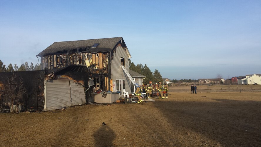 Firefighters form the 92nd Civil Engineering Squadron perform mop up and overhaul duties on a house Jan.15, 2014, after they successfully helped put out the fire with Spokane Fire Department District 10 firefighters. (U.S. Air Force photo by Kimo Kuheana)   