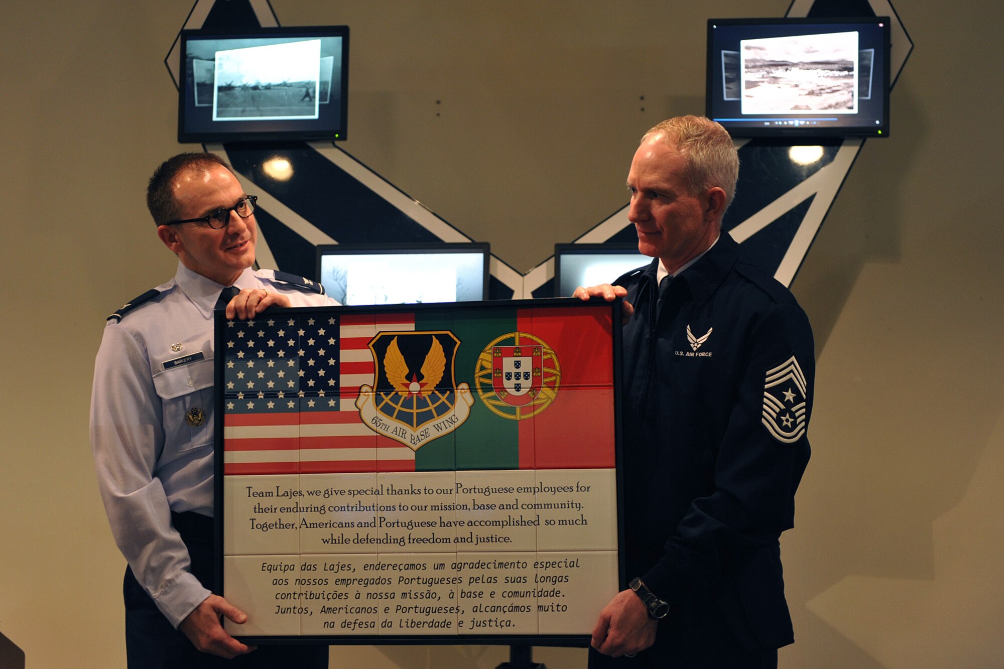 Col. Chris Bargery, 65th Air Base Wing commander, and Chief Master Sgt. Alan Boling, 65th ABW command chief, offer thanks to the Portuguese workforce with a commemorative gift during a Portuguese Employee Appreciation Month luncheon Jan. 24. The gift depicted the Portuguese and American flags flying side-by-side.  It will be displayed near the entrance of the Top of the Rock Club. (U.S. Air Force photo by Staff Sgt. Angelique N. Smythe)  