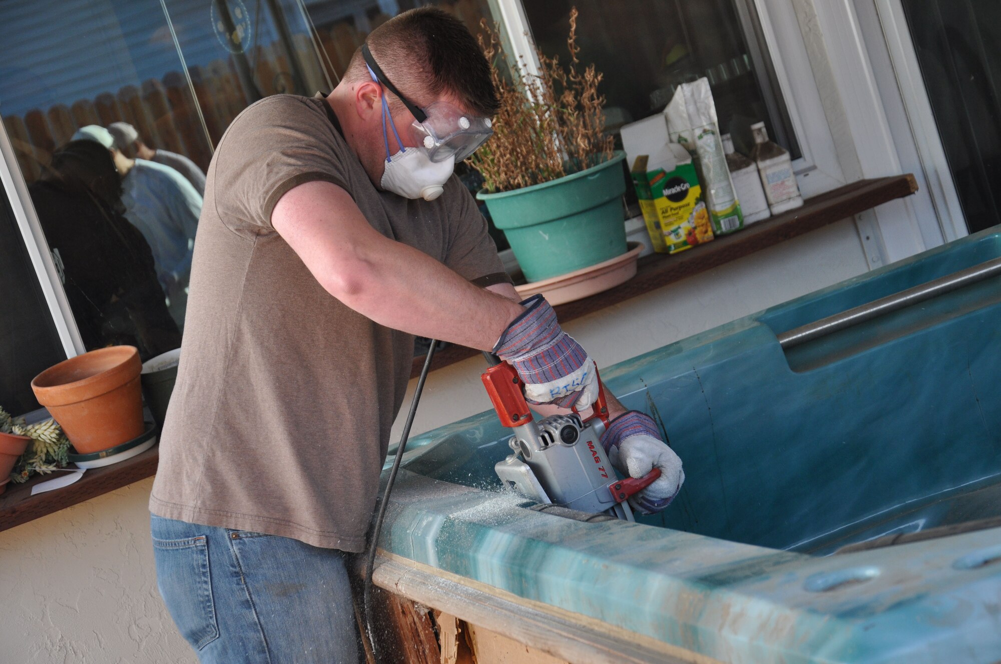 Senior Airman Justin Devine, 60th Medical Support Squadron medical administration, cuts into a hot tub during a volunteer event on Martin Luther King Jr. day hosted by Rebuilding Together Solano County in Fairfield. Airmen from Travis volunteered to help two local retired Air Force veterans, Victor Kestner of Fairfield and Jim Daniels of Vacaville, repair the interior and exterior of their homes. (U.S. Air Force photo/Staff Sgt. Christopher Carranza)