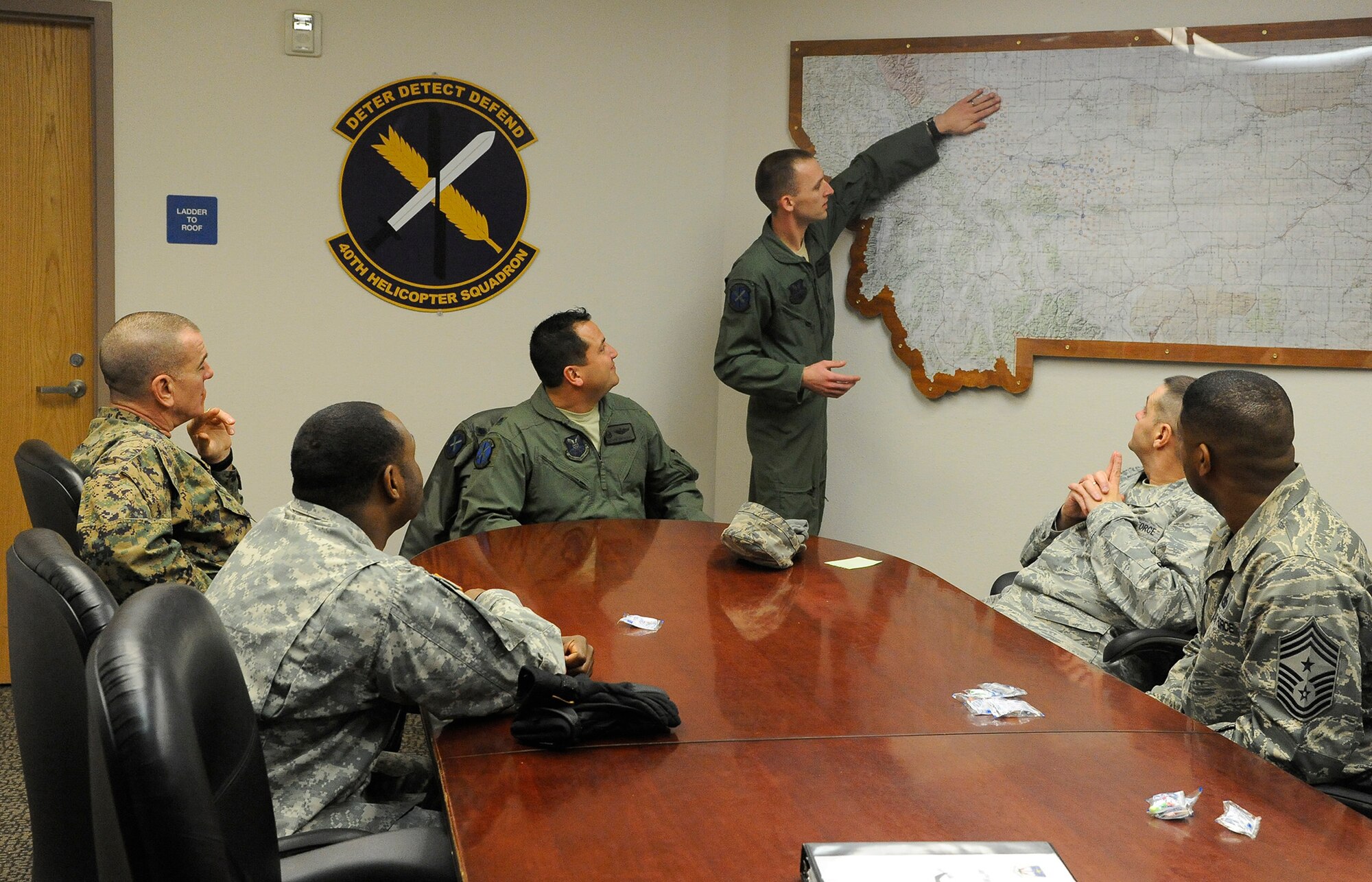 Staff. Sgt. Mike Frank, 40th Helicopter Squadron evaluator special mission aviator (standing), explains the size of the flight area within Malmstrom’s missile complex to Sgt. Maj. Bryan Battaglia, Senior Enlisted Advisor to the Chairman of the Joint Chiefs of Staff, and his colleagues at the helicopter squadron operations headquarters on Jan. 17. During the meeting, Battaglia was briefed on the 40th HS’s areas of responsibility as well as the capabilities of Malmstrom’s UH-1N Huey helicopters.  (U.S. Air Force photo/Airman 1st Class Collin Schmidt)