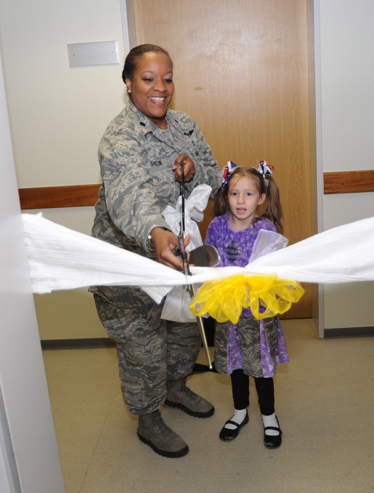 U.S. Air Force Lt. Col. Michele Shelton, commander of 52nd Medical Operations Squadron, and Aubrey Cappiello, five-year-old daughter of Master Sgt. Mark Cappiello, superintendent of weapons and tactics of 606th Air Control Squadron, cut a ceremonial ribbon at the opening of the new Family Play Group play room at Spangdahlem Air Base, Germany, Jan. 21, 2014. The play group allows parents to meet people and offer support through friendship and unity. (U.S. Air Force photo by Airman 1st Class Dylan Nuckolls/Released)