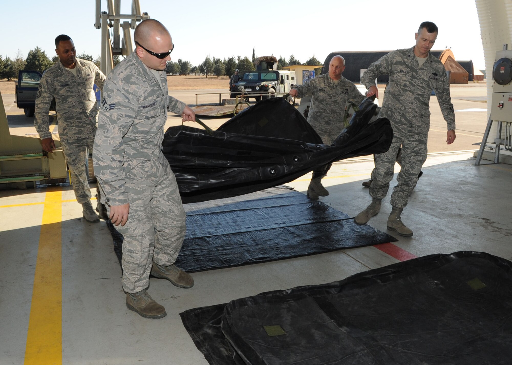 Airmen from the 39th Maintenance Squadron work with Col. Craig Wills, 39th Air Base Wing commander, and Chief Master Sgt. Anthony Johnson, 39th ABW command chief to move a pneumatic airbag in place as a demonstration of the squadrons Crash Disabled Damaged Aircraft Recovery capability Jan. 23, 2014, at Incirlik Air Base, Turkey. (U.S. Air Force photo by Staff Sgt. Veronica Pierce/Released) 