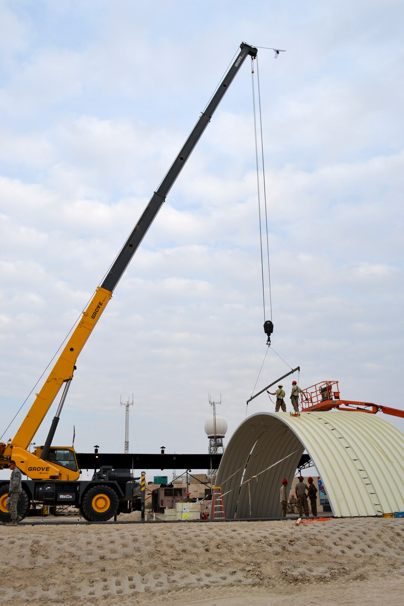 Members of the 557th Red Horse Squadron, 1st Expeditionary Civil Engineer Group based at Al Udeid, Qatar attach sections of a K-Span rapidly erectable structure in place during construction.  The Red Horse team was forward deployed to The Rock at the request of the 386th Expeditionary Civil Engineer Squadron to build the structure to house  power production Airmen and their generators.  The $350,000 structure is replacing older, temporary facilities and will add capability and increase quality of life for the 386th CES Airmen.  (U.S. Air Force photo by Senior Master Sgt. Pamela Anderson)