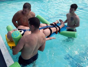 Firefighters from Joint Task Force-Bravo's 612 Air Base Squadron practice loading a patient with a spinal injury onto a backboard during water rescue training at the Soto Cano Air Base swimming pool, Jan. 24, 2014.  Training in pool allowed the firefighters to practice proper procedures for conducting rescue operations while in the water.  (U.S. Air Force photo by Tech. Sgt. Stacy Rogers)