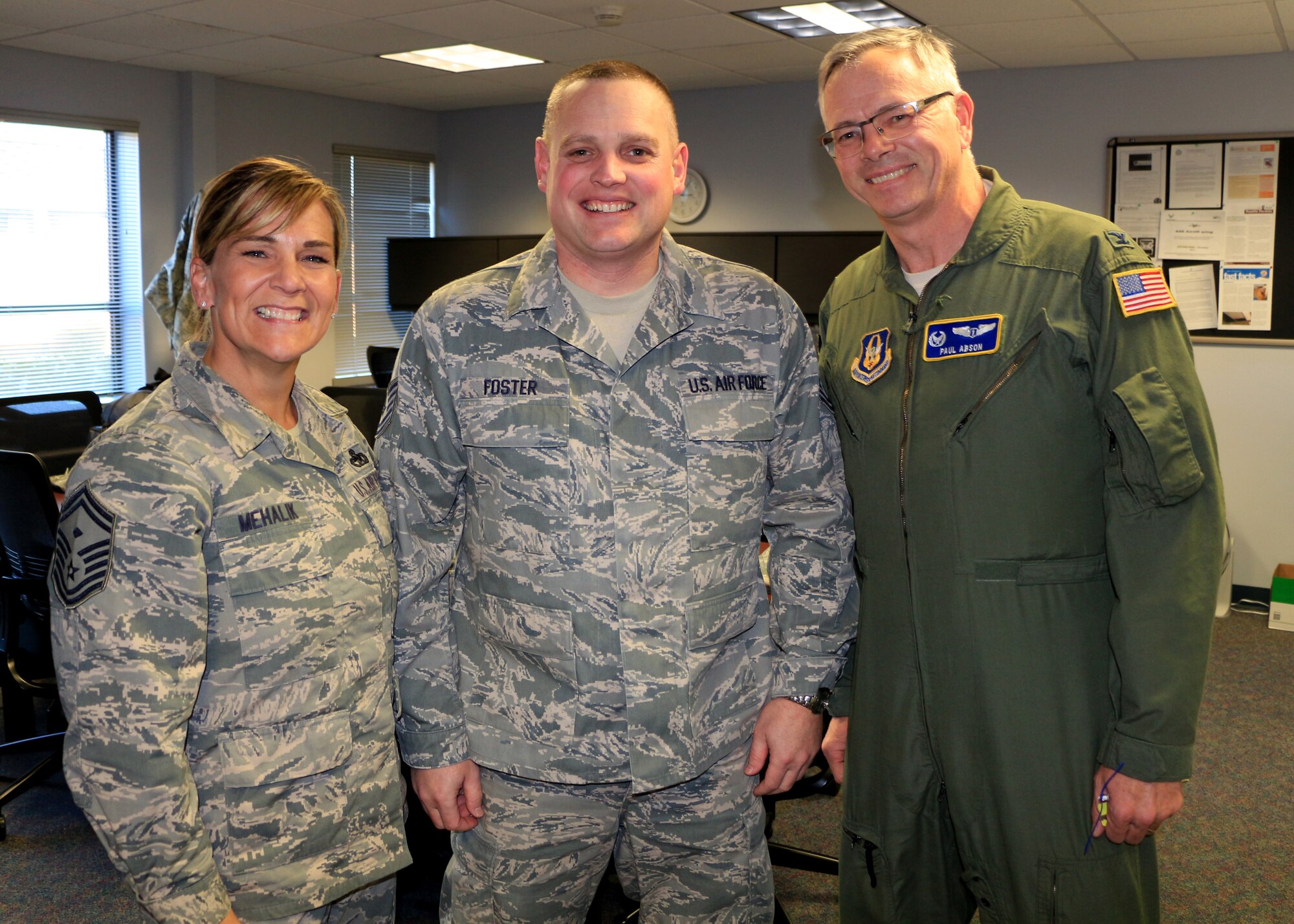 From left to right, Senior Master Sgt. Shannon Mehalik, Tech. Sgt. Darin Foster, and Col. Paul Abson smile for a photo after Abson surprised Foster with the news of his selection as first sergeant for the 446th Aerospace Medicine Squadron. Foster is leaving his position in the 446th Airlift Wing safety office for the new position. (U.S. Air Force Reserve photo by Senior Airman Madelyn McCullough)