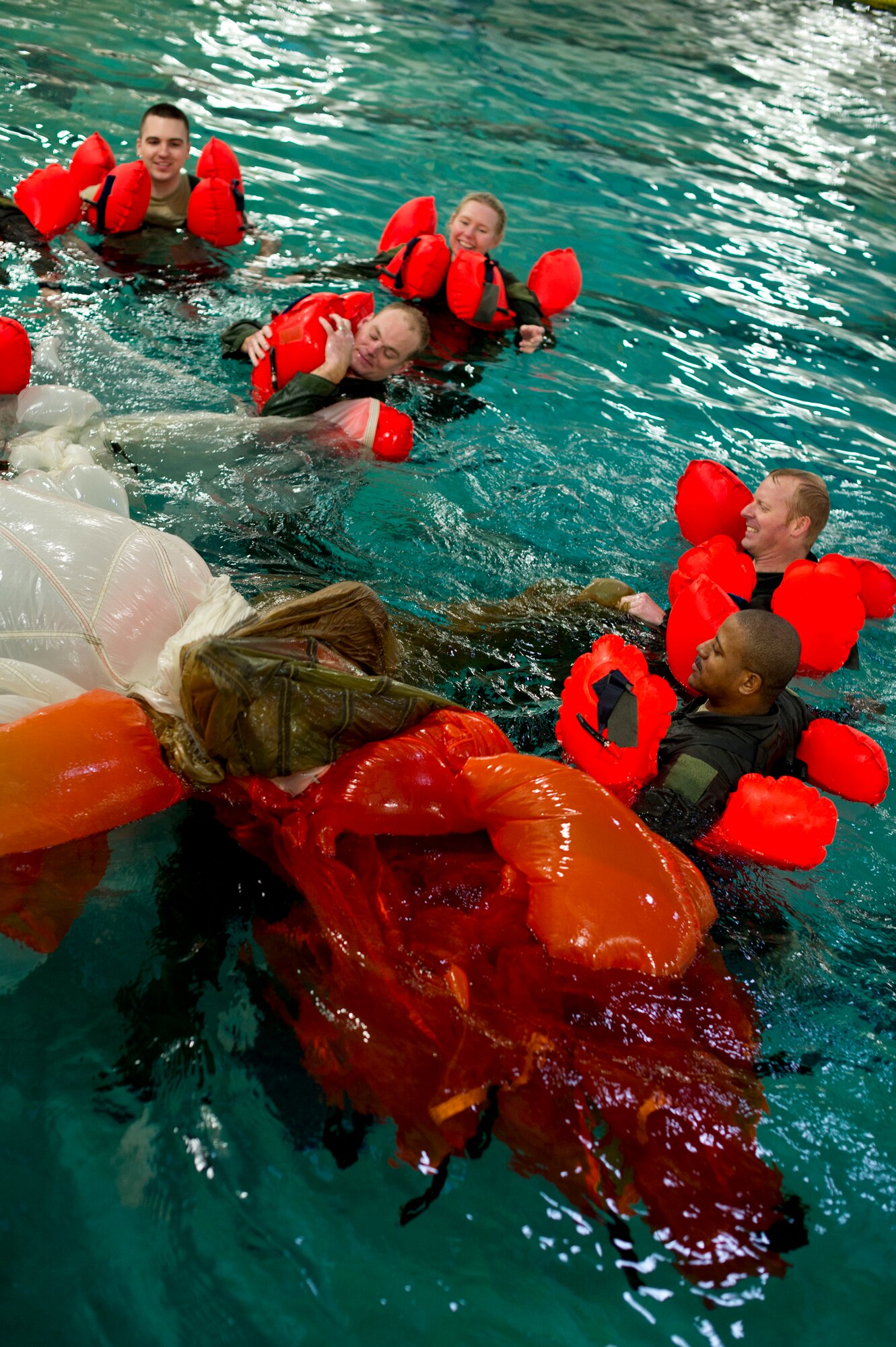 Airmen from the 133rd Operations Group take turns going underneath a parachute to simulate being entangled during water survival training at Foss Swim School in Eden Prairie, Minn., Jan 24, 2014. Water survival training encompasses equipment familiarization and processes in the event of an emergency over-water ditching scenario. (U.S. Air National Guard photo by Staff Sgt. Austen Adriaens/Released)