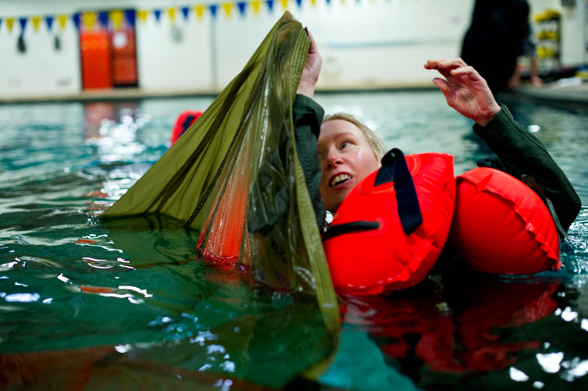 An aircrew member of the 133rd Operations Group prepares to make her way underneath a parachute during water survival training at Foss Swim School in Eden Prairie, Minn., Jan 24, 2014. Airmen had to climb under the parachute and come out on the other side unassisted to prepare them for an over-water ditching scenario. (U.S. Air National Guard photo by Staff Sgt. Austen Adriaens/Released)