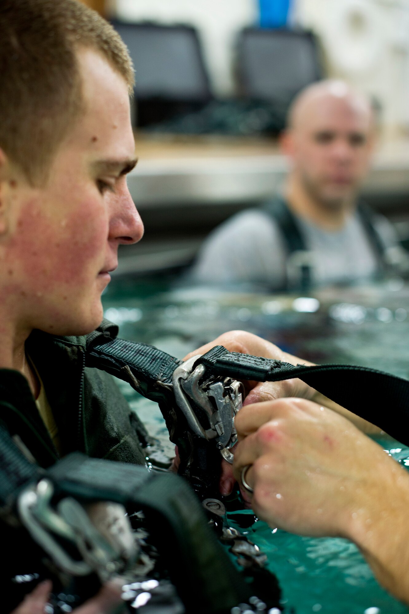 An aircrew member of the 133rd Operations Group receives help attaching his harness to simulate a parachute drag during water survival training at Foss Swim School in Eden Prairie, Minn., Jan 24, 2014. Water survival training encompasses equipment familiarization and processes in the event of an emergency over-water ditching scenario. (U.S. Air National Guard photo by Staff Sgt. Austen Adriaens/Released)