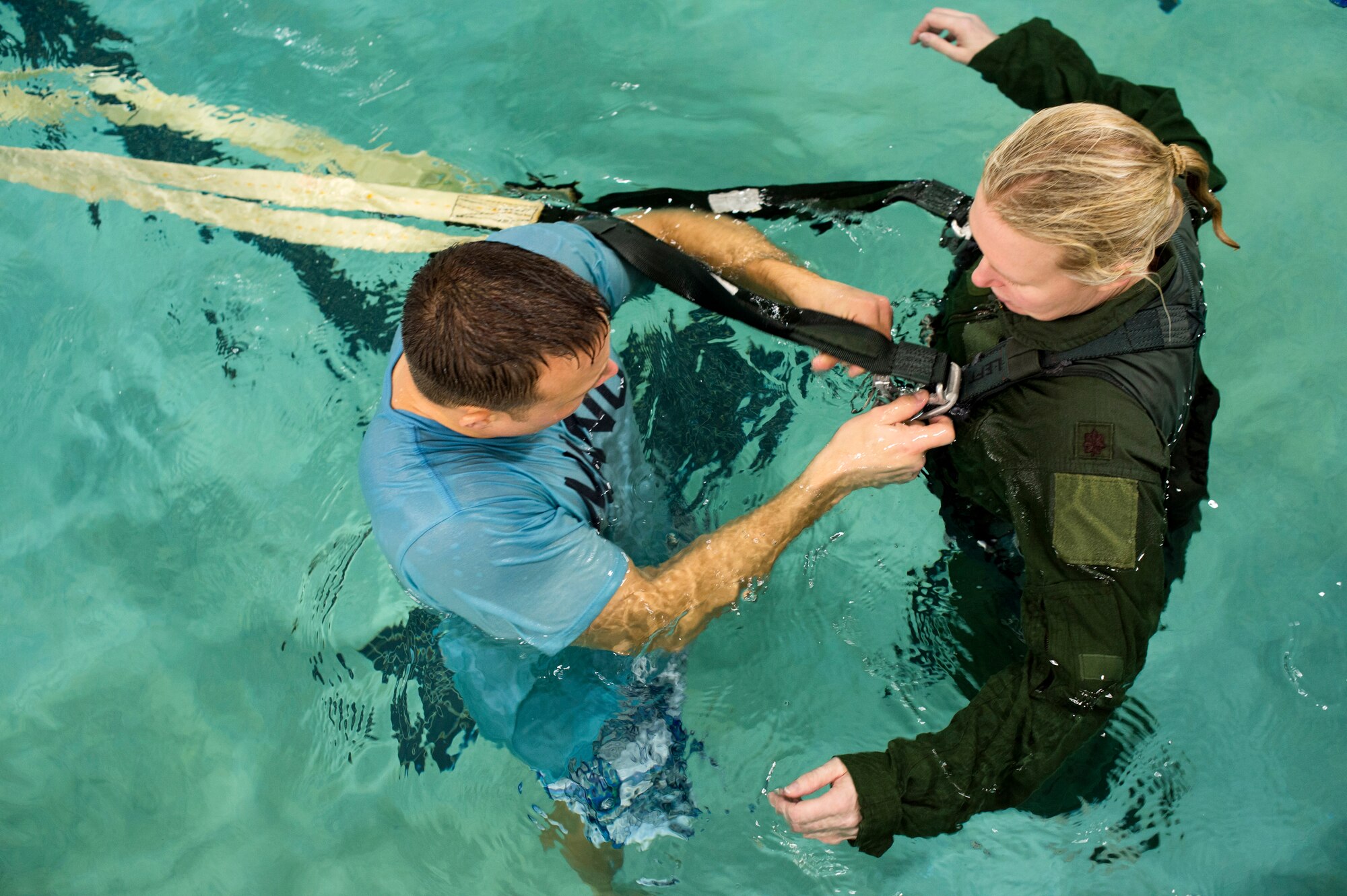 Senior Master Sgt. Aaron Siek hooks an aircrew member of the 133rd Operations Group to a restraint harness to simulate a parachute drag during water survival training at Foss Swim School in Eden Prairie, Minn., Jan 24, 2014. Water survival training encompasses equipment familiarization and processes in the event of an emergency over-water ditching scenario.  (U.S. Air National Guard photo by Staff Sgt. Austen Adriaens/Released)