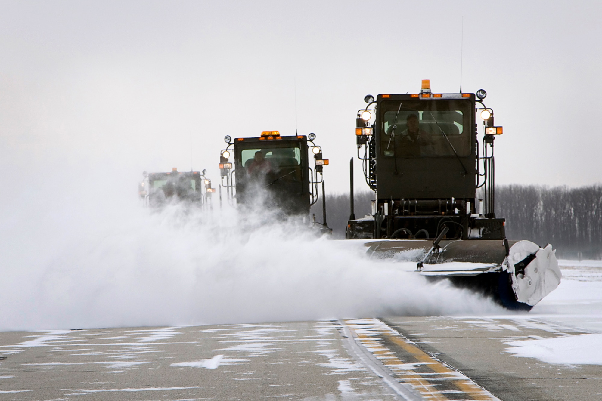 John Smith, Garth McClain and Moe Morgan, civilian contractors, remove snow from the runway at Grissom Air Reserve Base, Ind., Jan. 25, 2014, using multipurpose sweepers. After historic January snowfalls, civilian contractors have had to work hard to clear snow from Grissom's flightline so aircraft could continue to take off. (U.S. Air Force photo/Staff Sgt. Andrew McLaughlin)