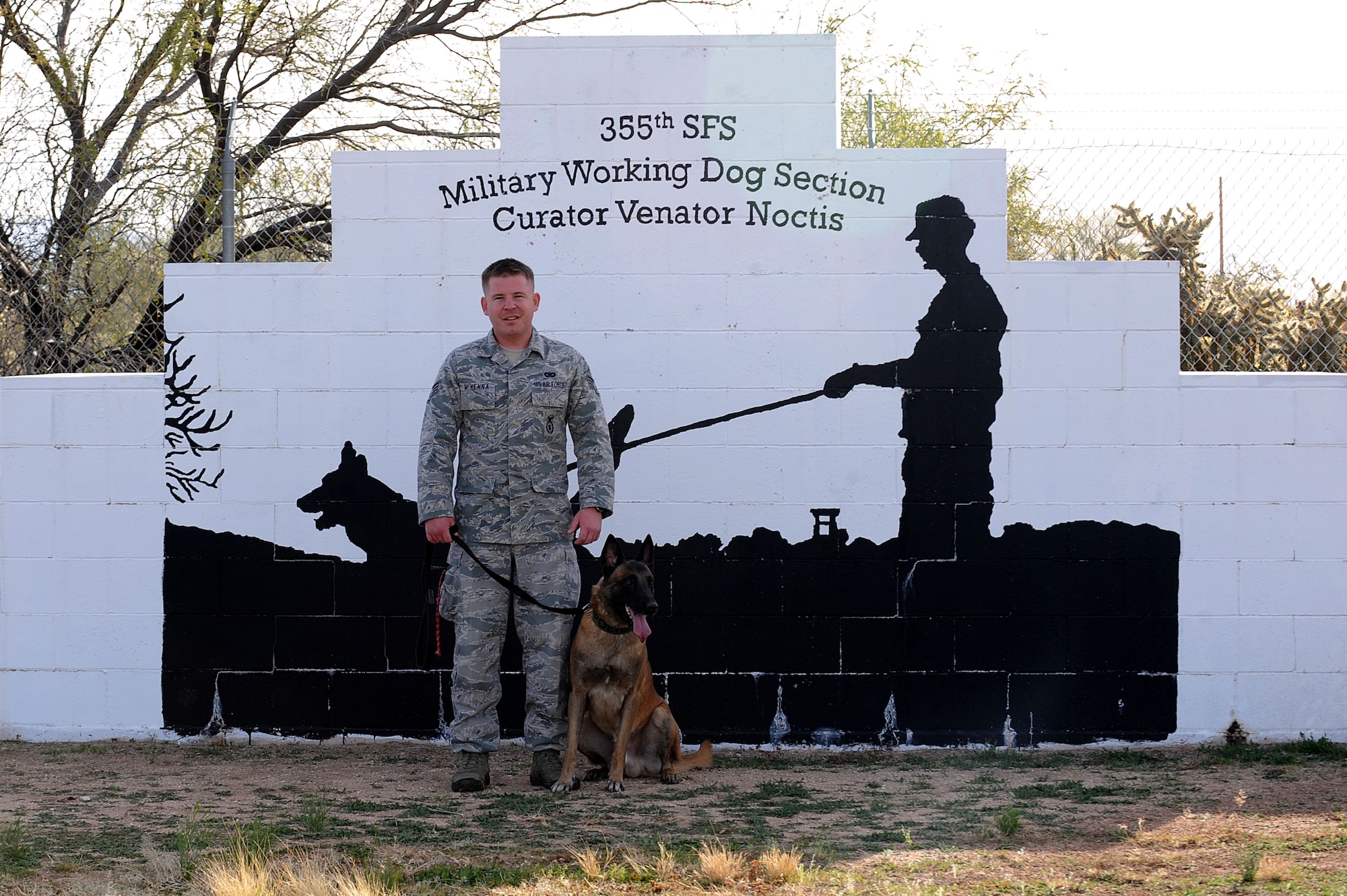 U.S. Air Force Staff Sgt. Sean McKenna, 355th Security Forces Squadron Military Working Dog handler, Mushe, 355th SFS MWD, pose for a photo during obedience training at Davis-Monthan Air Force Base, Ariz., Jan. 23, 2014. Mushe is trained as a patrol dog as well as an explosives detective dog and will apply both at his deployed location. (U.S. Air Force photo by Senior Airman Camilla Elizeu/Released)
