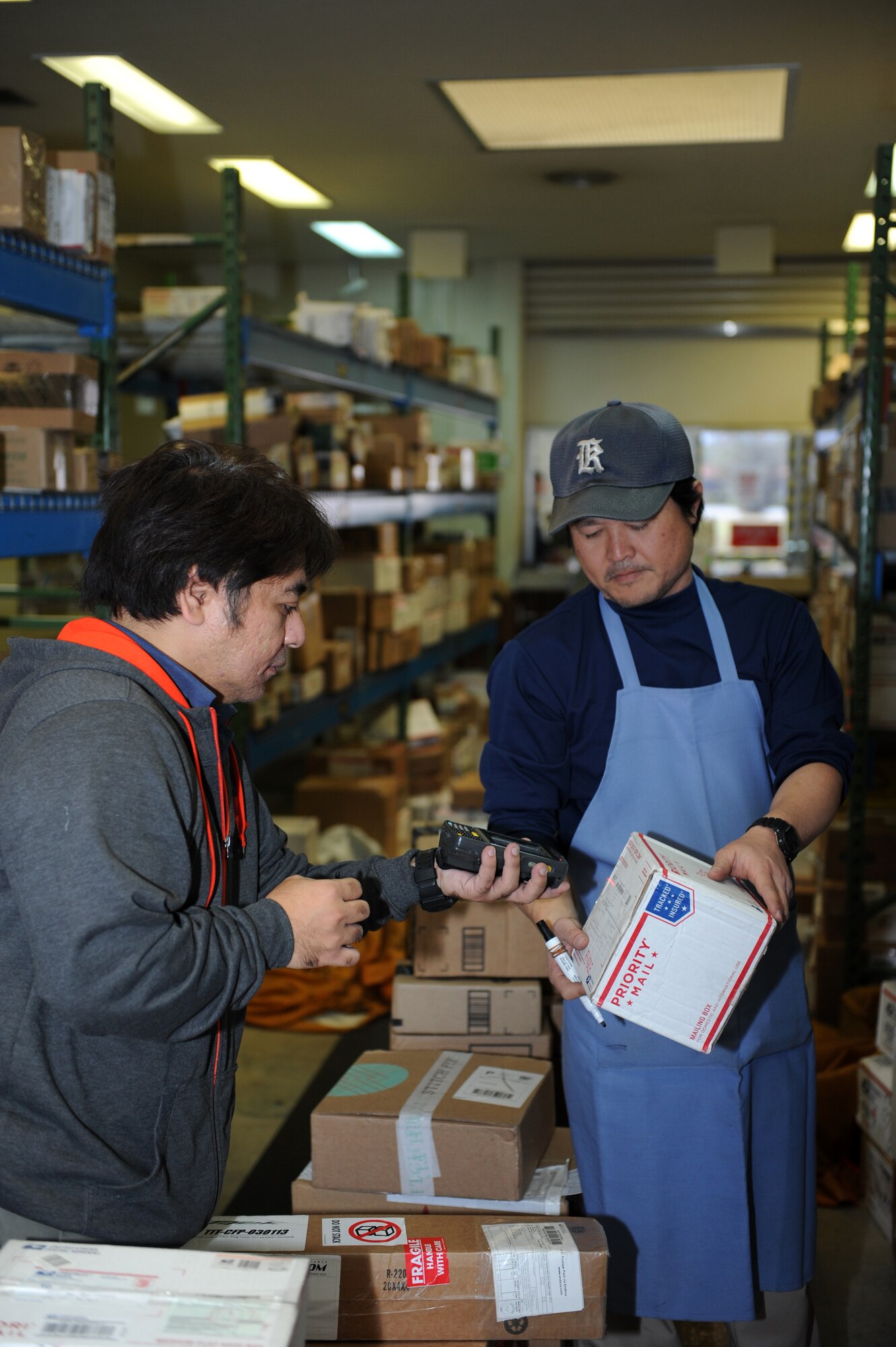 Yutaka Takaesu and Hiromichi Ginama, 18th Communications Squadron post office workers, process a parcel at the post office on Kadena Air Base, Japan, Jan. 23, 2014. The post office offers a variety of services ranging from mailing out parcels, money orders, parcel pick up, and an email notification system, as well as an official mailing center for mission-related shipments. (U.S. Air Force photo by Airman 1st Class Hailey R. Staker)