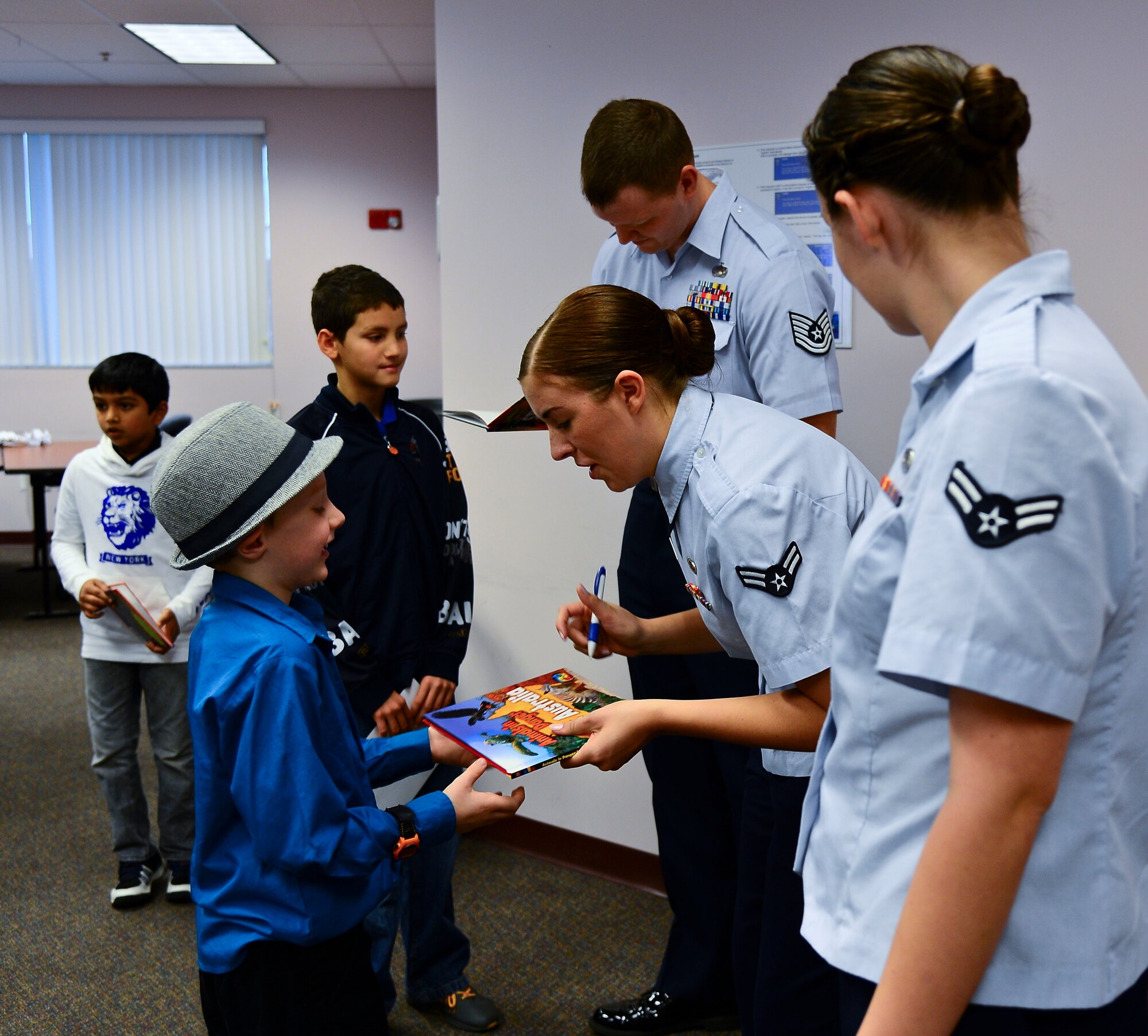 From right: Airman 1st Class Tori Schultz, 6th Air Mobility Wing public affairs photographer, Airman 1st Class Carly Thompson and Tech Sgt. George Maddon, 6th AMW public affairs broadcasters, sign books at the “Read on myON” Hillsborough County Public Schools awards breakfast Jan. 27, 2014. The Airmen helped represent the local hometown heroes at the breakfast. (U.S. Air Force photo by Airman 1st Class Vernon L. Fowler Jr./Released)