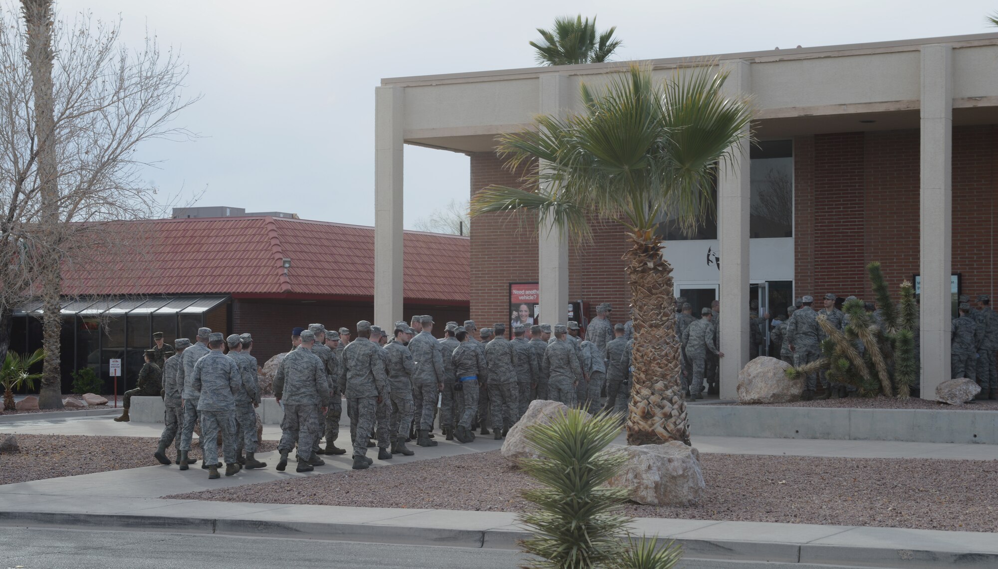 Airmen stand in line while entering the Nellis Air Force Base, Nev., theater Jan. 26, 2014. More than 66 units from the Department of Defense, British Royal Air Force and Royal Australian Air Force attend briefings. The units receive mission specific knowledge about the combat exercise Red Flag 14-1, which will take place throughout the next few weeks. (U.S. Air Force photo by Senior Airman Benjamin Sutton/Released)