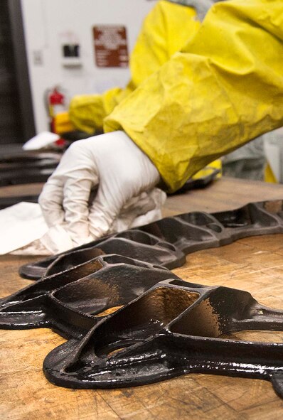 Fluorescent magnetic particles are removed from the plate backing of brake pads for a B-52H Stratofortress during a Magnetic Particle inspection at Minot Air Force Base, N.D., Jan. 21, 2014. If the particles are not removed, they may be harmful to the part when subject to further use. (U.S. Air Force photo/Senior Airman Stephanie Sauberan)   