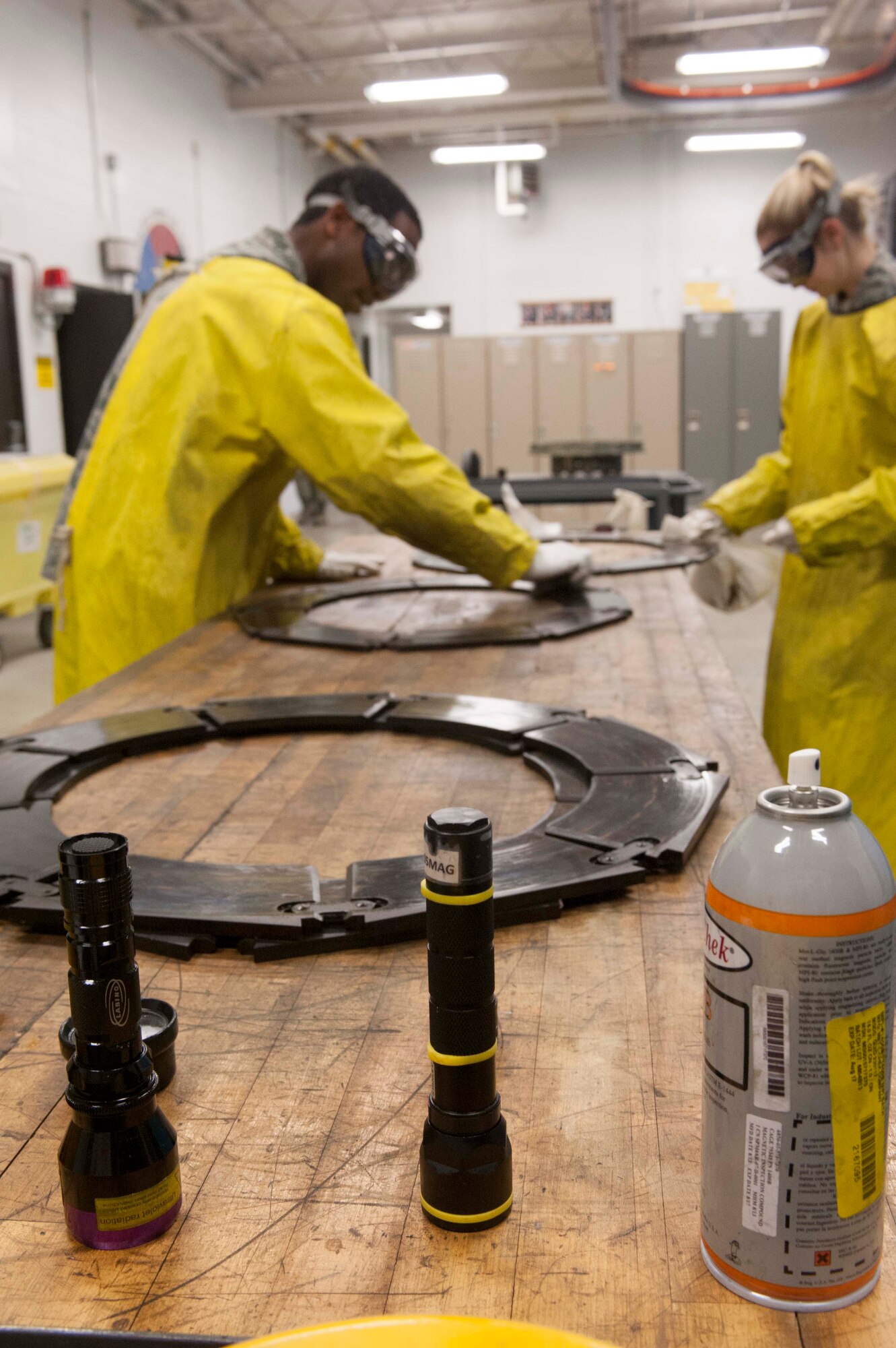 (from left to right) Airman 1st Class Clarence Tobias and Airman 1st Class Courtney Harrah, 5th Maintenance Group non-destructive inspection apprentices, remove fluorescent magnetic particles from the brake pads of a B-52H Stratofortress during a Magnetic Particle inspection at Minot Air Force Base, N.D., Jan. 21, 2014. The fluorescent magnetic particles used in a magnetic particle bath are attracted to the leakage fields created by discontinuities.  (U.S. Air Force photo/Senior Airman Stephanie Sauberan)   