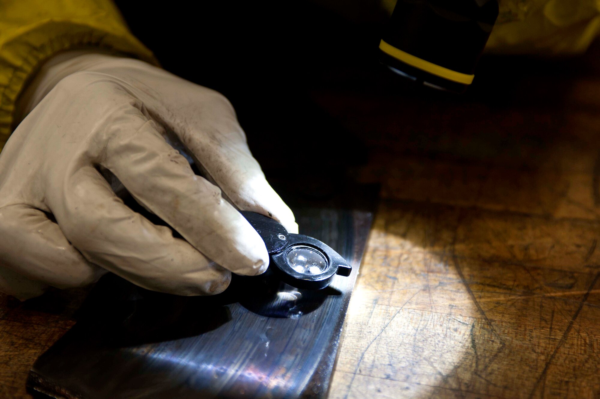 A small magnifying glass is used to verify flaw indications found on the brake pads of a B-52H Stratofortress during a Magnetic Particle inspection at Minot Air Force Base, N.D., Jan. 21, 2014. A crack indication on a flawed part will usually present itself as a thin, continuous, jagged line. (U.S. Air Force photo/Senior Airman Stephanie Sauberan)   