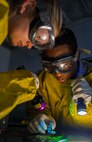 (from left to right) Airman 1st Class Courtney Harrah and Airman 1st Class Clarence Tobias, 5th Maintenance Group non-destructive inspection apprentices, perform a Magnetic Particle inspection on the brake pads of a B-52H Stratofortress at Minot Air Force Base, N.D., Jan. 21, 2014. The fluorescent magnetic particles used on the brake pad will "fluoresce" under a black light, providing a contrast with the part and allowing identification of any flaws. A crack indication will usually present itself as a thin, continuous, jagged line. (U.S. Air Force photo/Senior Airman Stephanie Sauberan)   