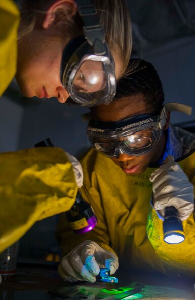 (from left to right) Airman 1st Class Courtney Harrah and Airman 1st Class Clarence Tobias, 5th Maintenance Group non-destructive inspection apprentices, perform a Magnetic Particle inspection on the brake pads of a B-52H Stratofortress at Minot Air Force Base, N.D., Jan. 21, 2014. The fluorescent magnetic particles used on the brake pad will "fluoresce" under a black light, providing a contrast with the part and allowing identification of any flaws. A crack indication will usually present itself as a thin, continuous, jagged line. (U.S. Air Force photo/Senior Airman Stephanie Sauberan)   