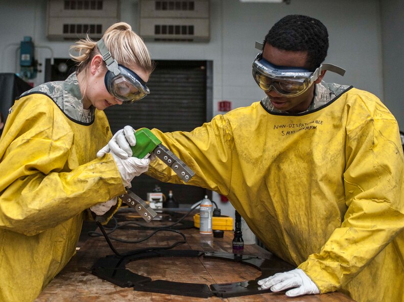 (from left to right)Airman 1st Class Courtney Harrah and Airman 1st Class Clarence Tobias, 5th Maintenance Group non-destructive inspection apprentices, magnetize the brake pads of a B-52H Stratofortress during a Magnetic Particle inspection at Minot Air Force Base, N.D., Jan. 21, 2014. To magnetize a part, it is either placed in the stationary magnetic particle inspection unit or a portable magnet (referred to as a parker probe) is used.  While the part is being magnetized, the inspector will apply the magnetic particle bath/vehicle which contains fluorescent magnetic particles.  (U.S. Air Force photo/Senior Airman Stephanie Sauberan)