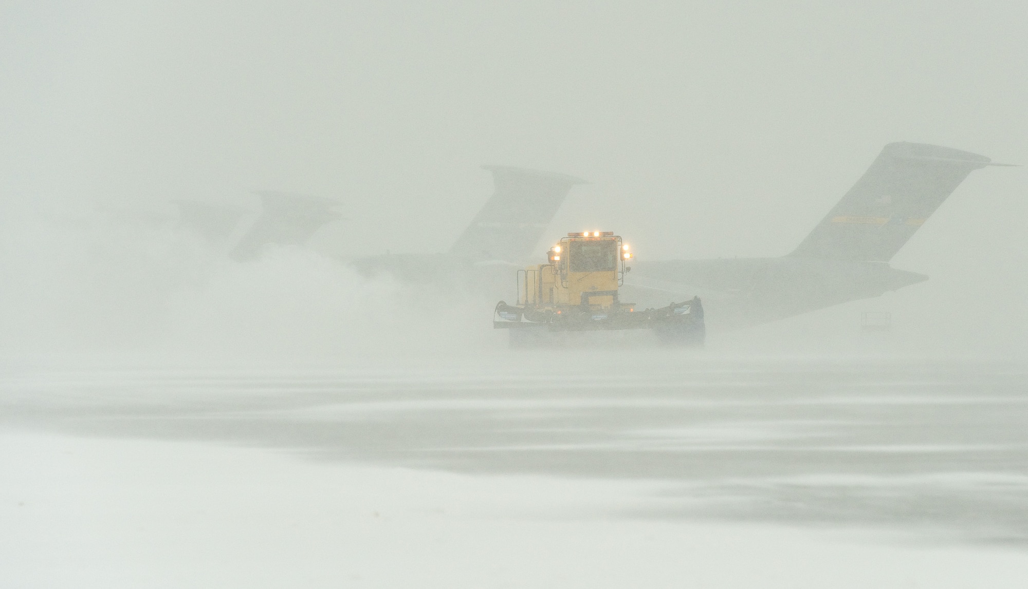 A snow plow from the 436th Civil Engineer Squadron clears snow from the flight line Jan. 21, 2014, at Dover Air Force Base, Del. Wind-driven snow fell at a rate of one inch per hour at times, making visibility limited to a half-mile. (U.S. Air Force photo/Roland Balik)