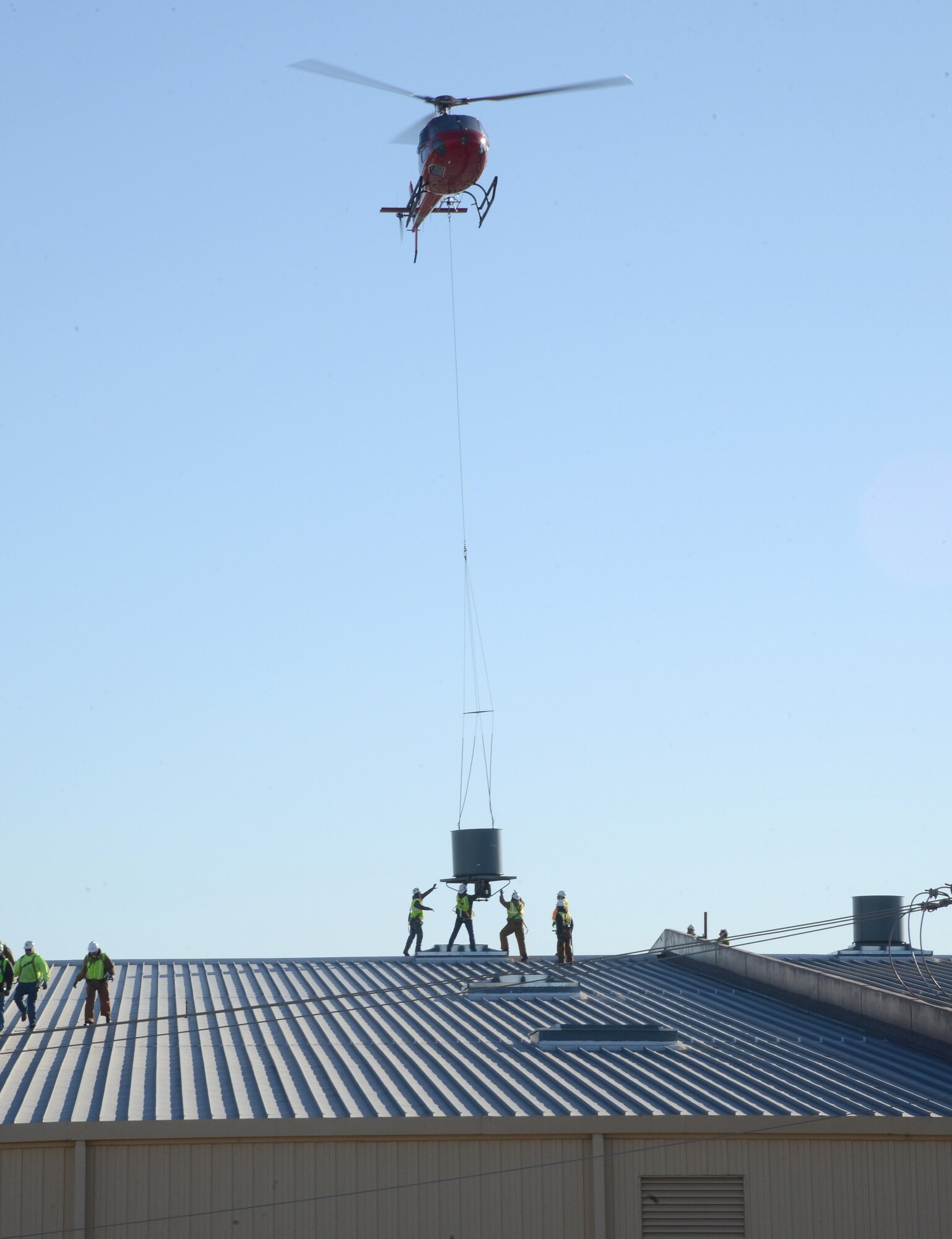 Workers from Trade Mechanical Contractors of Oklahoma City position one of 61 fans hoisted by helicopter to the roof of Bldg. 510 on Jan. 18. (Air Force photo by Kelly White)