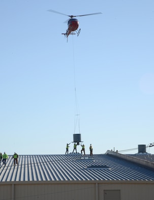 Workers from Trade Mechanical Contractors of Oklahoma City position one of 61 fans hoisted by helicopter to the roof of Bldg. 510 on Jan. 18. (Air Force photo by Kelly White)