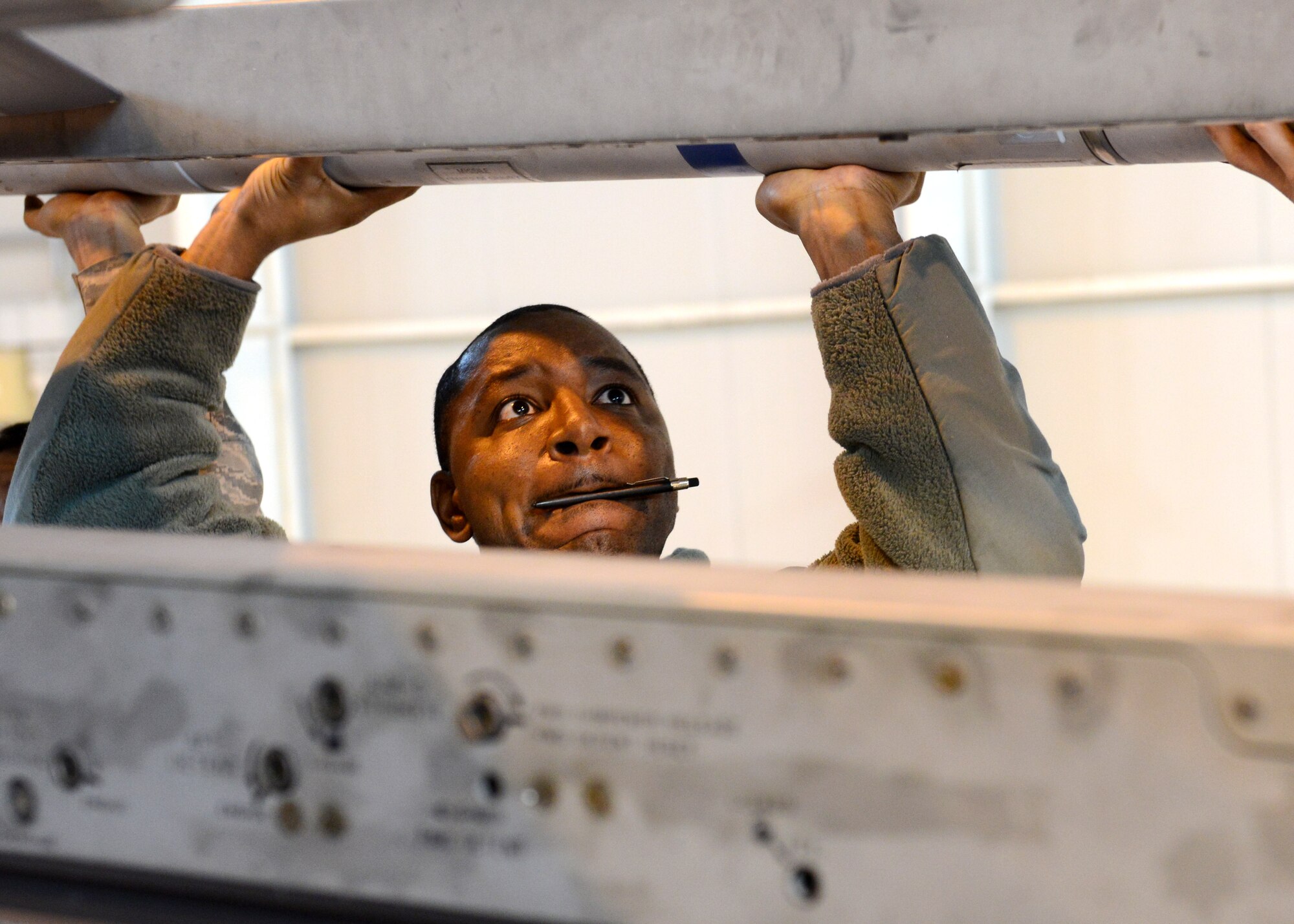 Staff Sgt. Nathaniel Seeney, 31st Aircraft Maintenance Squadron weapons load crew chief, helps secure munition to the wing of an F-16 Fighting Falcon during an annual weapons load crew competition, Jan. 23, 2014, at Aviano Air Base, Italy. Three three-person teams competed for the title of best weapons load crew of the year. (U.S. Air Force photo/Airman 1st Ryan Conroy) 