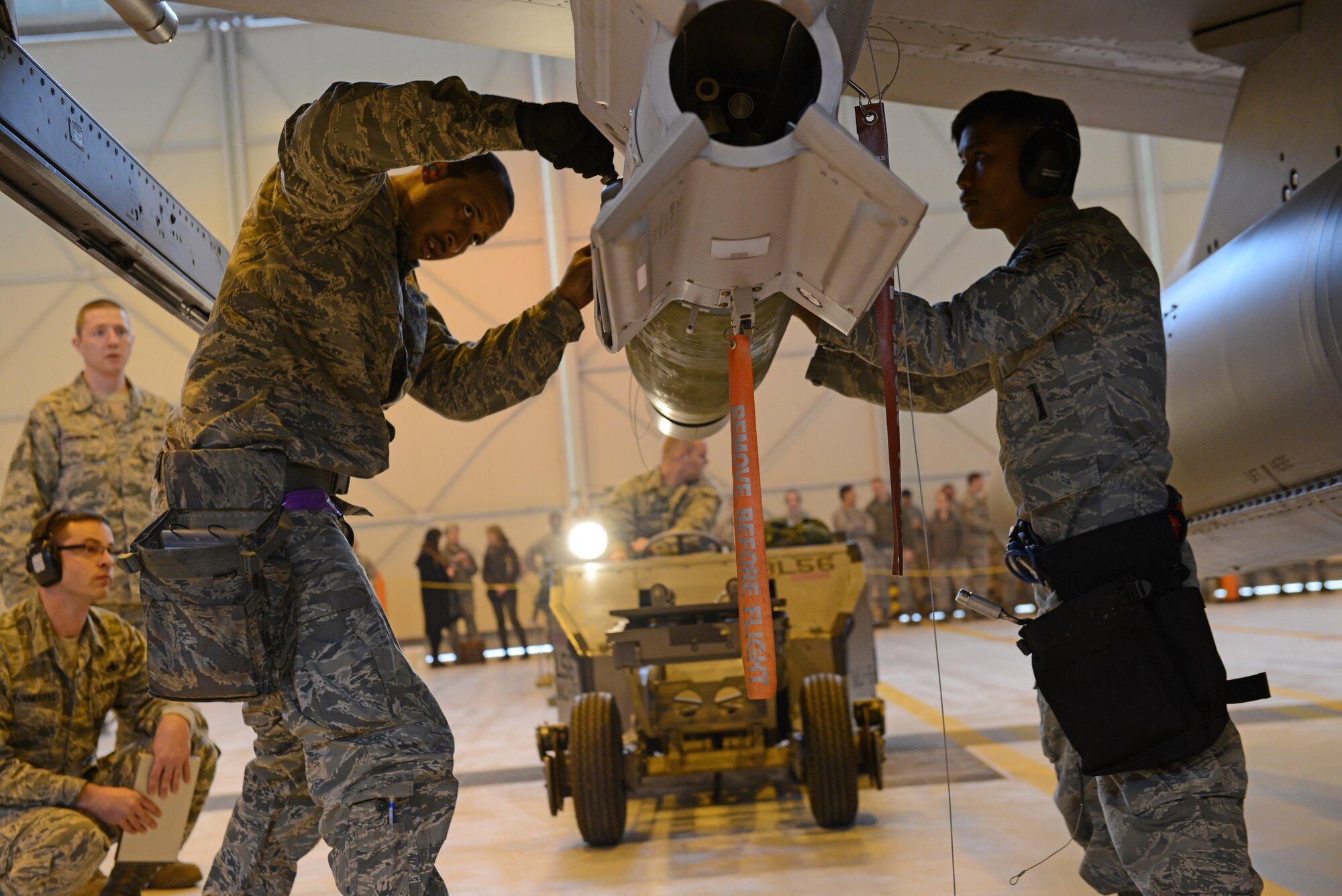 (From left) Staff Sgt. Steven James, 31st Aircraft Maintenance Squadron weapons load crew chief, and Senior Airman Bryan Ednave, 31st AMXS weapons load crew member, secure a munition to the wing of an F-16 Fighting Falcon during a weapons load competition, Jan. 23, 2014, at Aviano Air Base, Italy. Load crew competitions ensure Airmen maintain their skills while also promoting competition and camaraderie among the squadrons.  (U.S. Air Force photo/Airman 1st Class Ryan Conroy) 
