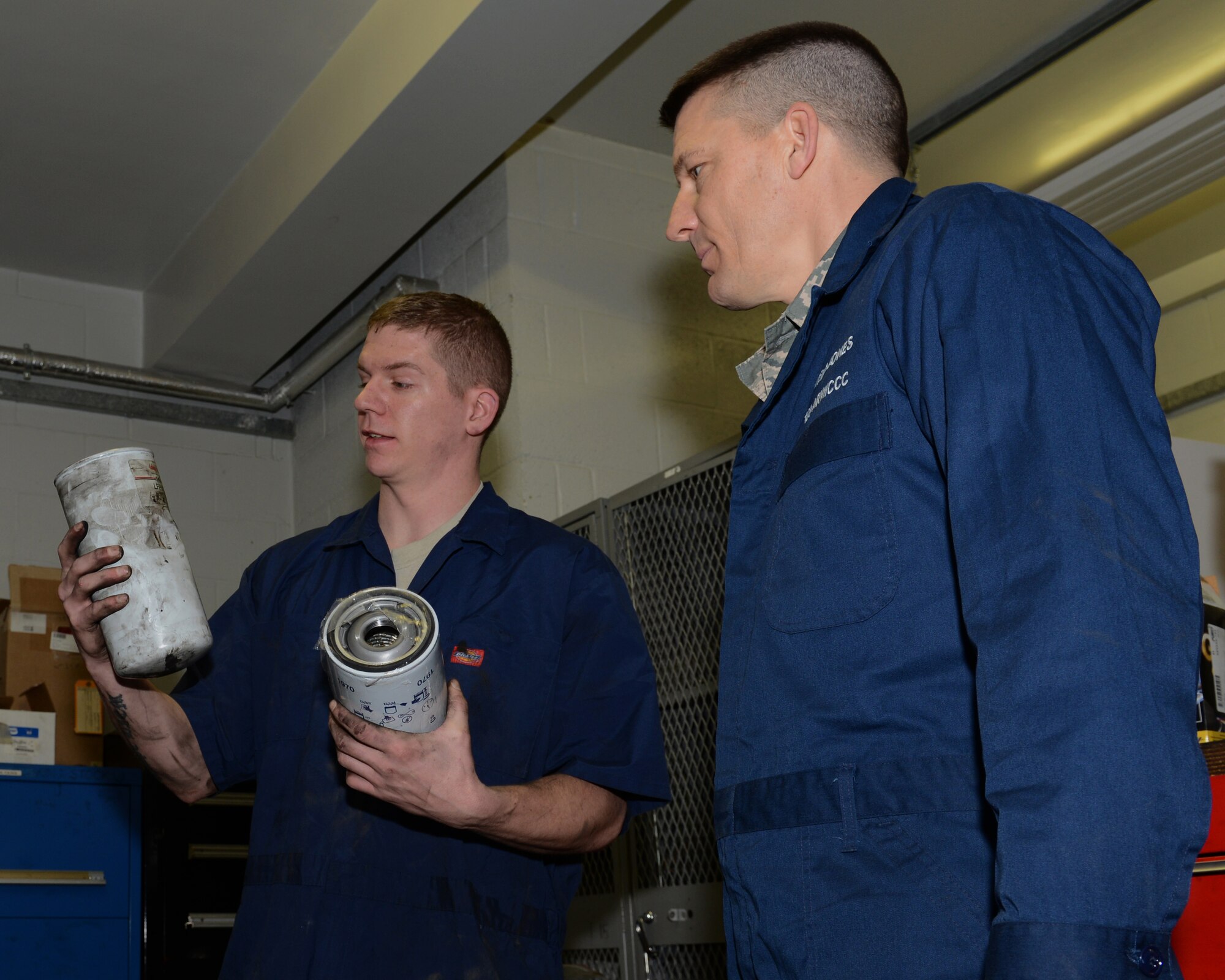 U.S. Air Force Senior Airman Jason Brown, left, 100th Logistics Readiness Squadron vehicle maintenance journeyman from Akron, Ohio, shows U.S. Air Force Chief Master Sgt. Tracy Jones, 100th Air Refueling Wing command chief, the difference between a new and used oil filter Jan. 23, 2014, on RAF Mildenhall, England. As part of the “Dirty Jobs” program Brown showed Jones how to perform routine maintenance. The “Dirty Jobs” program affords Airmen the opportunity to show base leadership first-hand what their jobs entail. (U.S. Air Force photo by Airman 1st Class Preston Webb/Released)