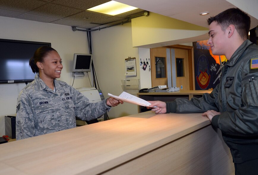 U.S. Air Force Senior Airman Monica Brown, 7th Special Operations Squadron aviation resource management journeyman from Cleveland, hands flight crew orders to Senior Airman Christopher Kerlee, 7th Special Operations Squadron loadmaster from Catania, Sicily, Jan. 15, 2014, on RAF Mildenhall, England. Brown earned the Square D Spotlight for exhibiting the Air Force Core Value of Service Before Self. (U.S. Air Force photo by Airman 1st Class Kyla Gifford/Released) 