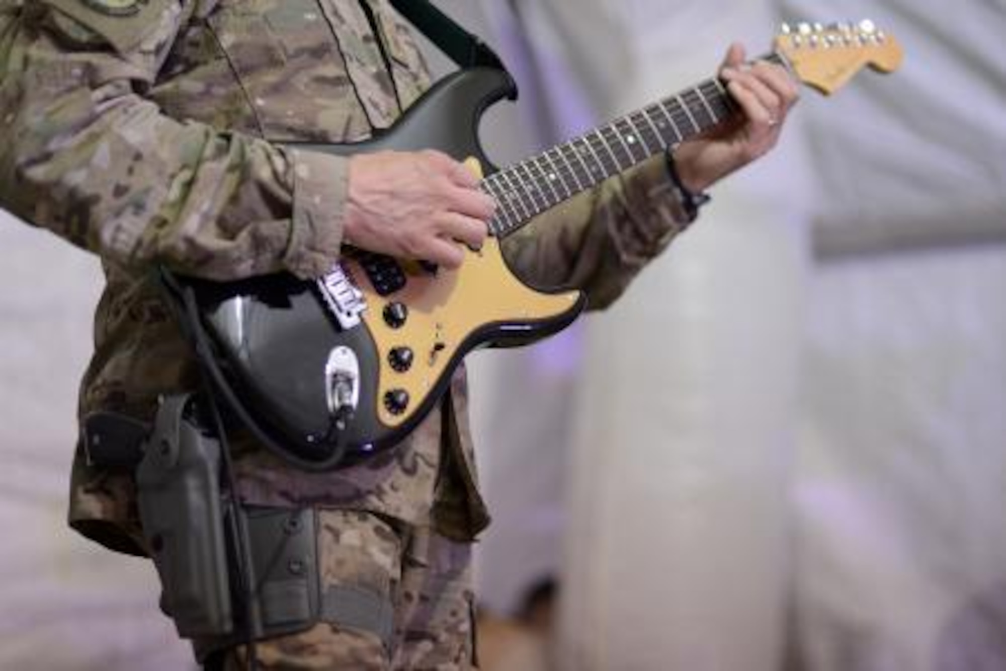 Master Sgt. Toby McWilliams, Air Force Central Command Band guitarist, performs at a concert venue for U.S., Italian and Afghan forces Dec. 14, 2013, at Shindand Airfield, Afghanistan. Mission requirements in Afghanistan require band members, and other service members, to be armed at all times. McWilliams, a Lubbock, Texas, native, is deployed from the Air Force Band of Flight, Wright Patterson, Air Force Base, Ohio. (U.S. Air Force photo by Tech. Sgt. Jason Robertson)

