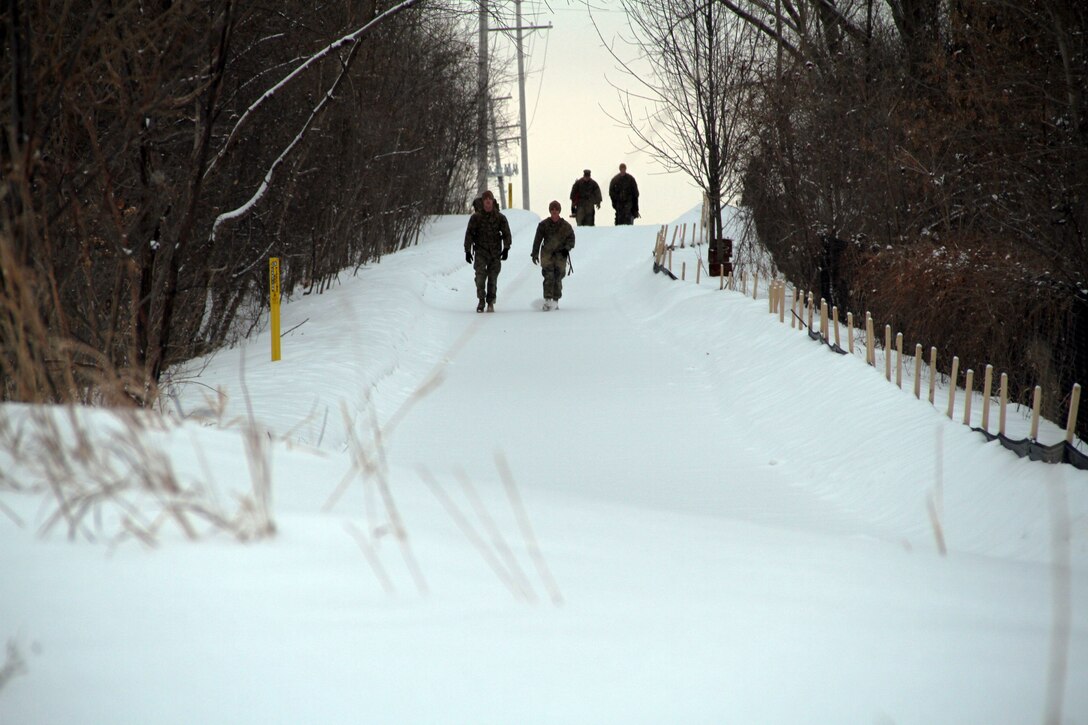 Marines with Marine Corps Recruit Station Twin Cities scout ahead of a group of female poolees on a hike, Jan. 26. During the hike, the poolees carried rubber rifles and heavily loaded packs to simulate the heavy burdens they will be expected to carry while in recruit training. 