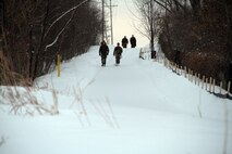 Marines with Marine Corps Recruit Station Twin Cities scout ahead of a group of female poolees on a hike, Jan. 26. During the hike, the poolees carried rubber rifles and heavily loaded packs to simulate the heavy burdens they will be expected to carry while in recruit training. 