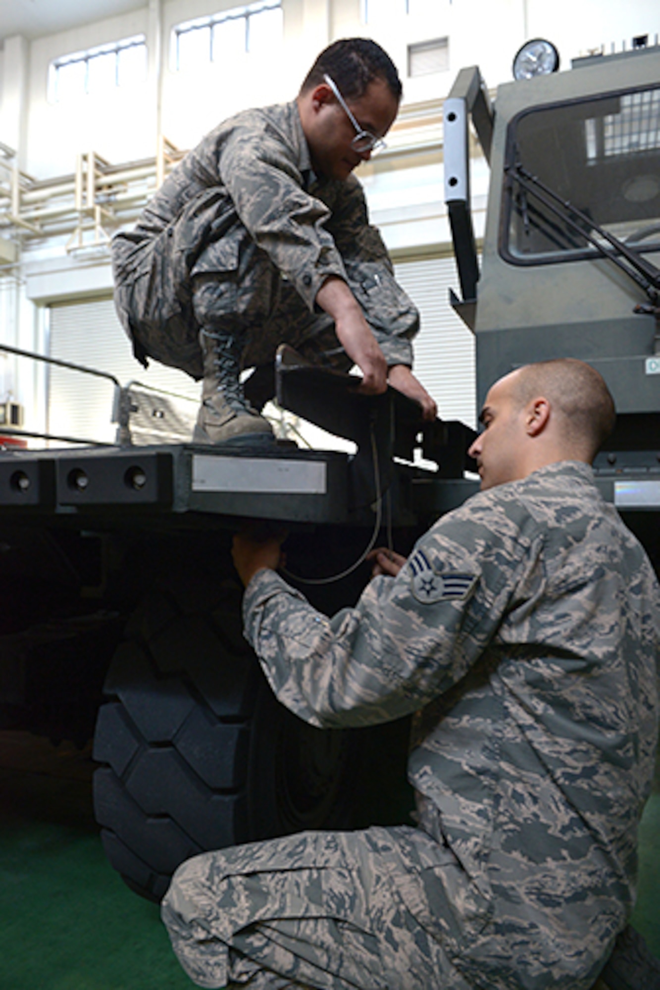 Staff Sgt. Angel Suarez, 374th Logistics Readiness Squadron non-commissioned officer in charge, and Senior Airman Clint Williams, 374th Logistics Readiness Squadron vehicle maintainer, work together to reconfigure a Halvorson 25K loader at Yokota Air Base, Japan, Jan. 24, 2014. Working together they reduce the chance for injury caused by pinch points. (U.S. Air Force photo by Airman 1st Class David Danford/Released)