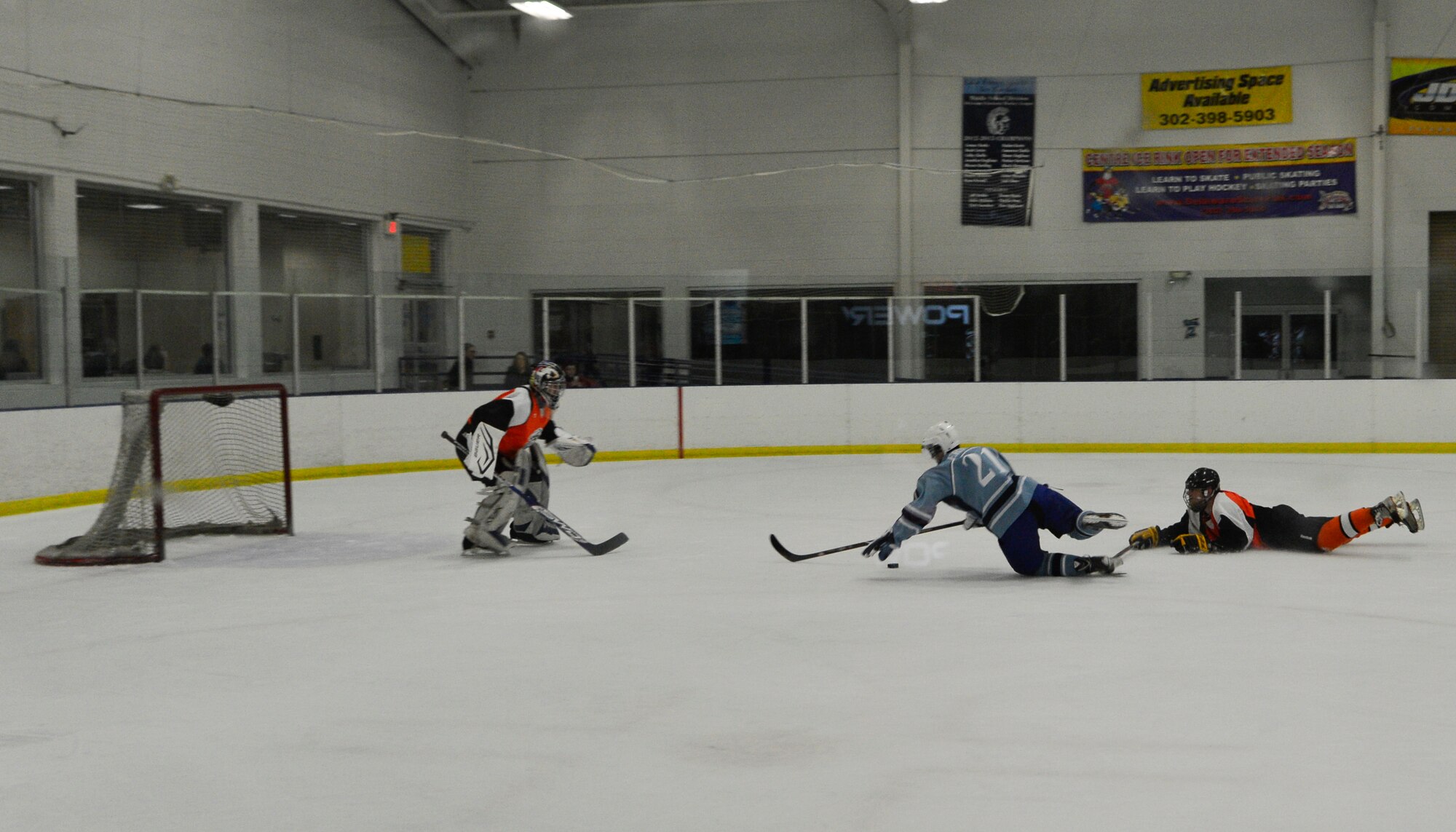 Sam Ernst, Dover Eagles center, and a Fraternal Order of Police defensemen fall as they go for the puck during a charity hockey game Jan. 26, 2014, at Centre Ice Rink in Harrington, Del. The game raised $1,130 for the Concerns of Police Survivors charity. (U.S. Air Force photo/Airman 1st Class William Johnson)
