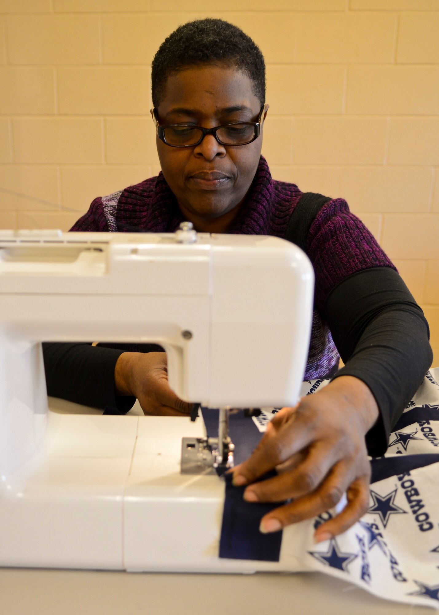Peggy Jones, 633rd Force Support Squadron quilting instructor, performs a sewing demonstration after the Community Commons ribbon-cutting ceremony at Langley Air Force Base, Va., Jan 24, 2014. The 633rd Mission Support Group plans to add sewing, scrapbooking, photography and videography classes to the Community Commons. (U.S. Air Force photo by Airman 1st Class Victoria H. Taylor/Released)