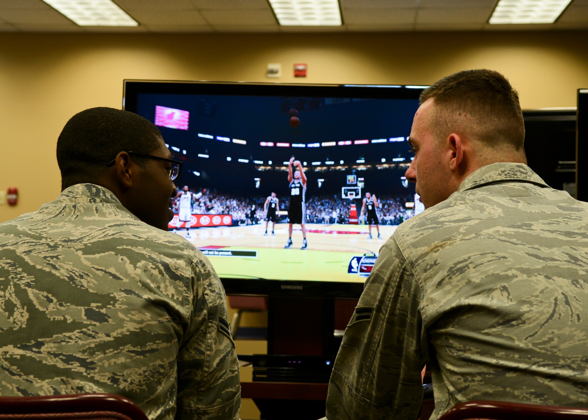 U.S. Air Force Airman 1st Class Fritz Javel, 633rd Force Support Squadron shift lead, and Airman 1st Class Kenny Warren, 633rd Force Support Squadron storage room assistant, compete in a video game before the Community Commons ribbon-cutting ceremony at Langley Air Force Base Va,. Jan 24, 2014. The new Community Commons, previously known as the Community Center, provides a central location for recreational and leisure activities for all base personnel. (U.S. Air Force photo by Airman 1st Class Victoria H. Taylor/Released)