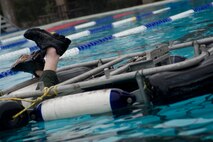 The feet of an aircrew member hang out of a rotary-wing aircraft seat apparatus in the base pool at Hurlburt Field, Fla., Jan. 27 2014. The training serves as a water-survival refresher training course that instructs aircrew how to successfully escape a submerged rotary-wing aircraft. The aircrew must successfully escape the apparatus for a simulated water landing. (U.S. Air Force photo/Senior Airman Naomi Griego)