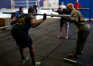 U.S. Marine Corps Gunnery Sgt. Juan Ospina, Joint Task Force-Civil Support current operations noncommissioned officer in charge, shows students proper exercise form at  Anderson Field House at Fort Eustis, Va., Jan. 27, 2014.  Ospina is a lead trainer for the Functional Fitness program, which uses general and inclusive fitness techniques that individuals use every day, such as squatting, running, jumping, and lifting, to prepare for physical contingencies.  (U.S. Air Force photo by Staff Sgt. Ciara Wymbs/Released)