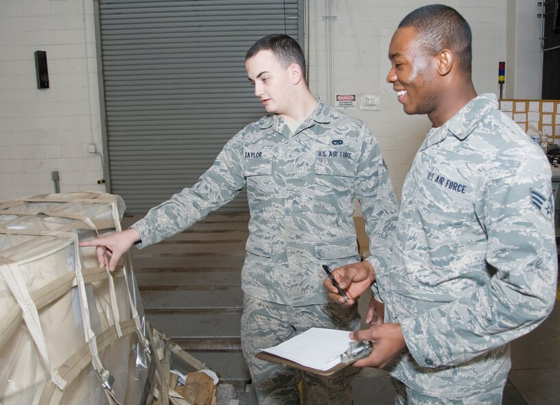 Senior Airman Kenneth Taylor, 436th Aerial Port Squadron cargo processor, talks with Senior Airman Stephen Yelbert, 436th Comptroller Squadron all things financial specialist, about how to query a pallet ensuring air readiness before storage Jan. 23, 2014, at the 436th APS on Dover Air Force Base, Del. Yelbert is embedded with the 436th APS to assist them with their financial issue such as travel vouchers, government travel card issues and monthly pay discrepancies.. (U.S. Air Force photo/Senior Airman Jared Duhon)